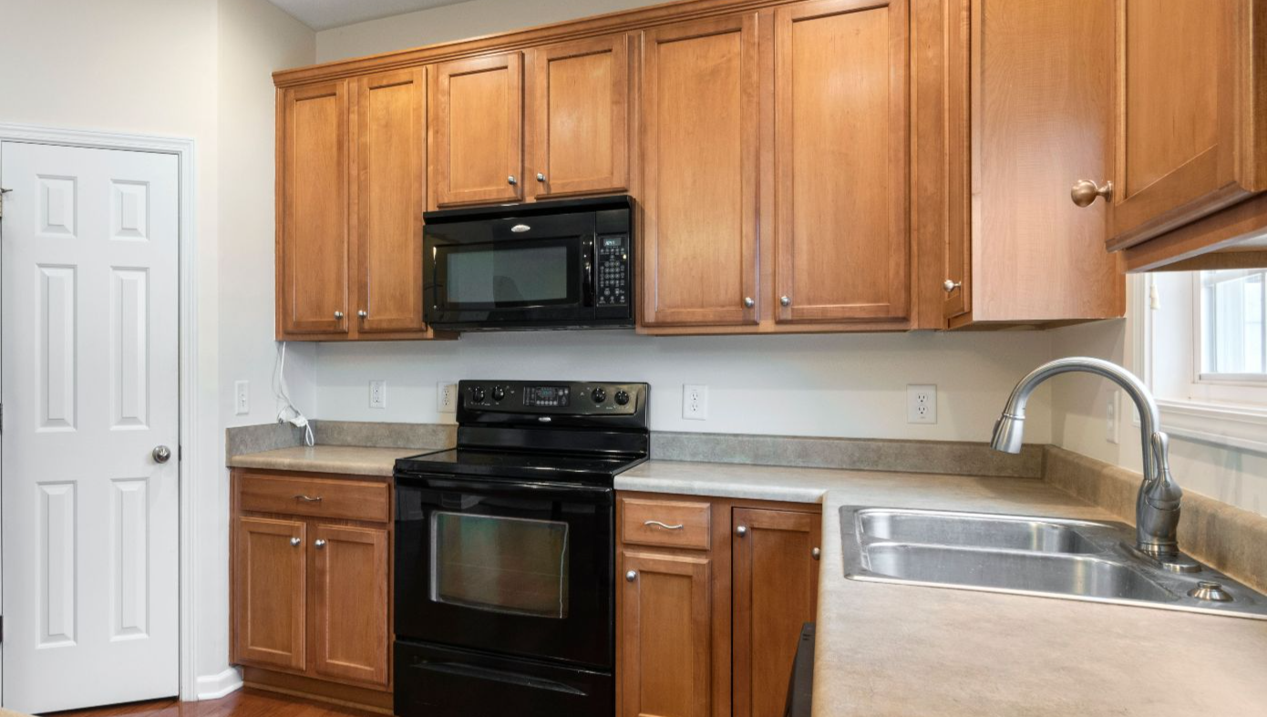 A spacious kitchen featuring wooden cabinets, black appliances, and a sleek countertop.