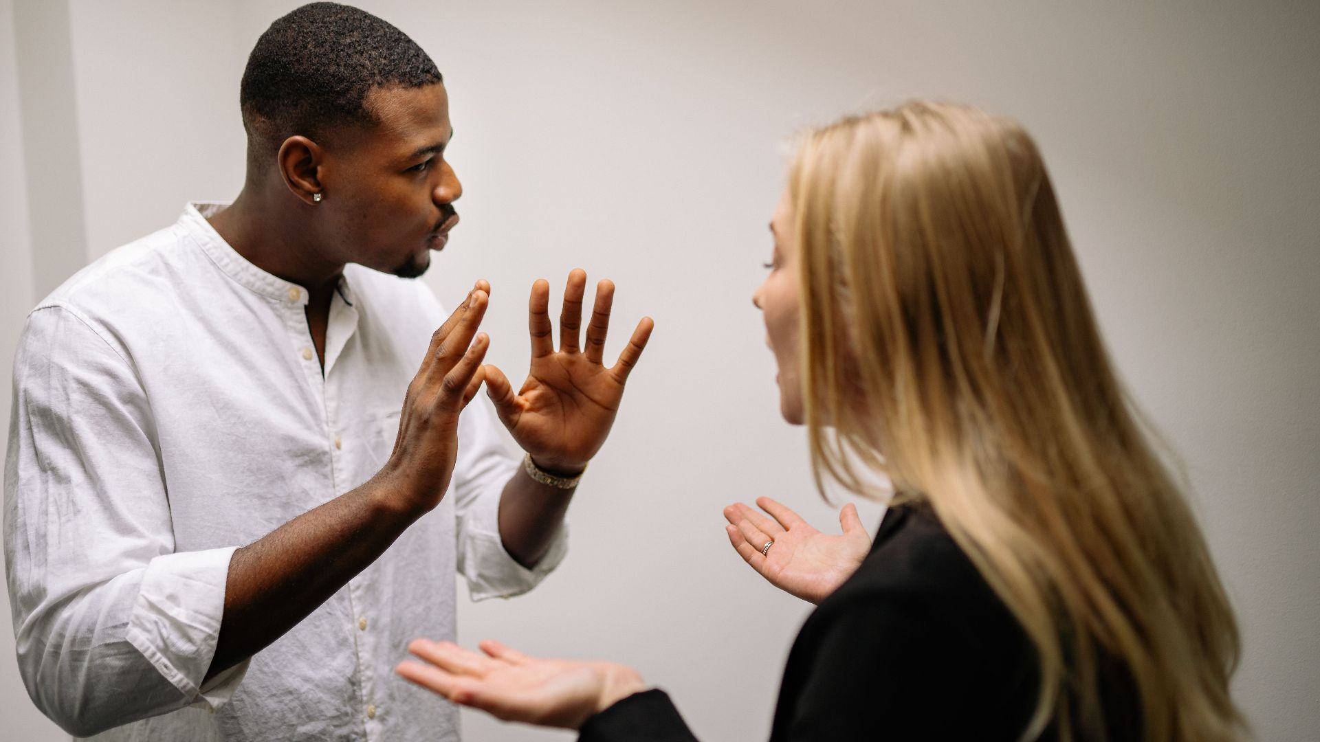 Frustrated coworkers in heated discussion, expressing disagreement in office setting.