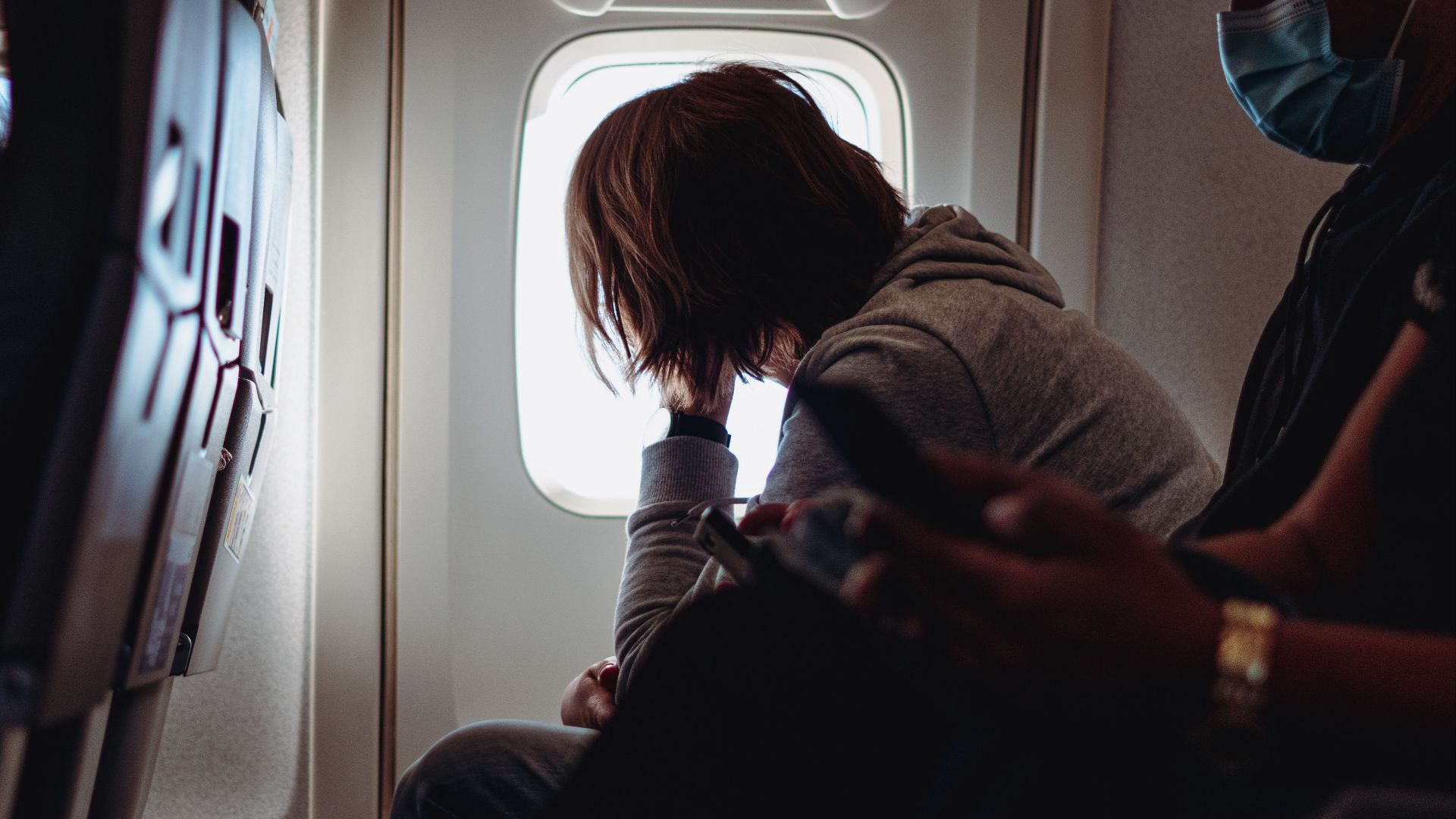 A passenger gazes out of an airplane window, reflecting on in-flight travel.