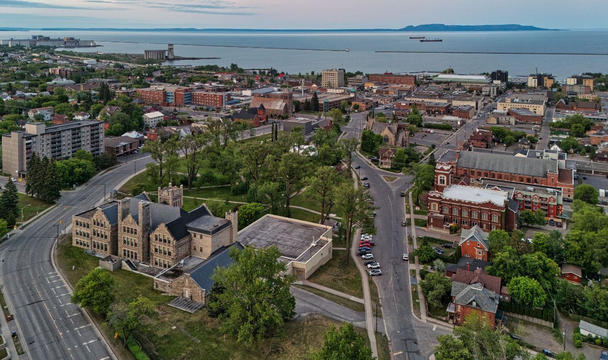 Aerial view of Thunder Bay, Ontario, showcasing historic buildings, roads, and Lake Superior in the background.