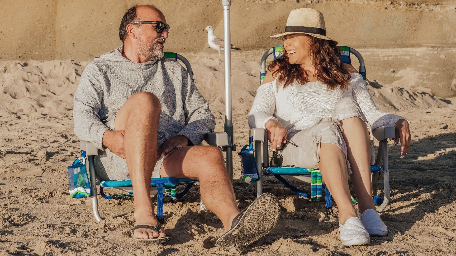 Happy senior couple seated on the beach enjoying a sunny day together.