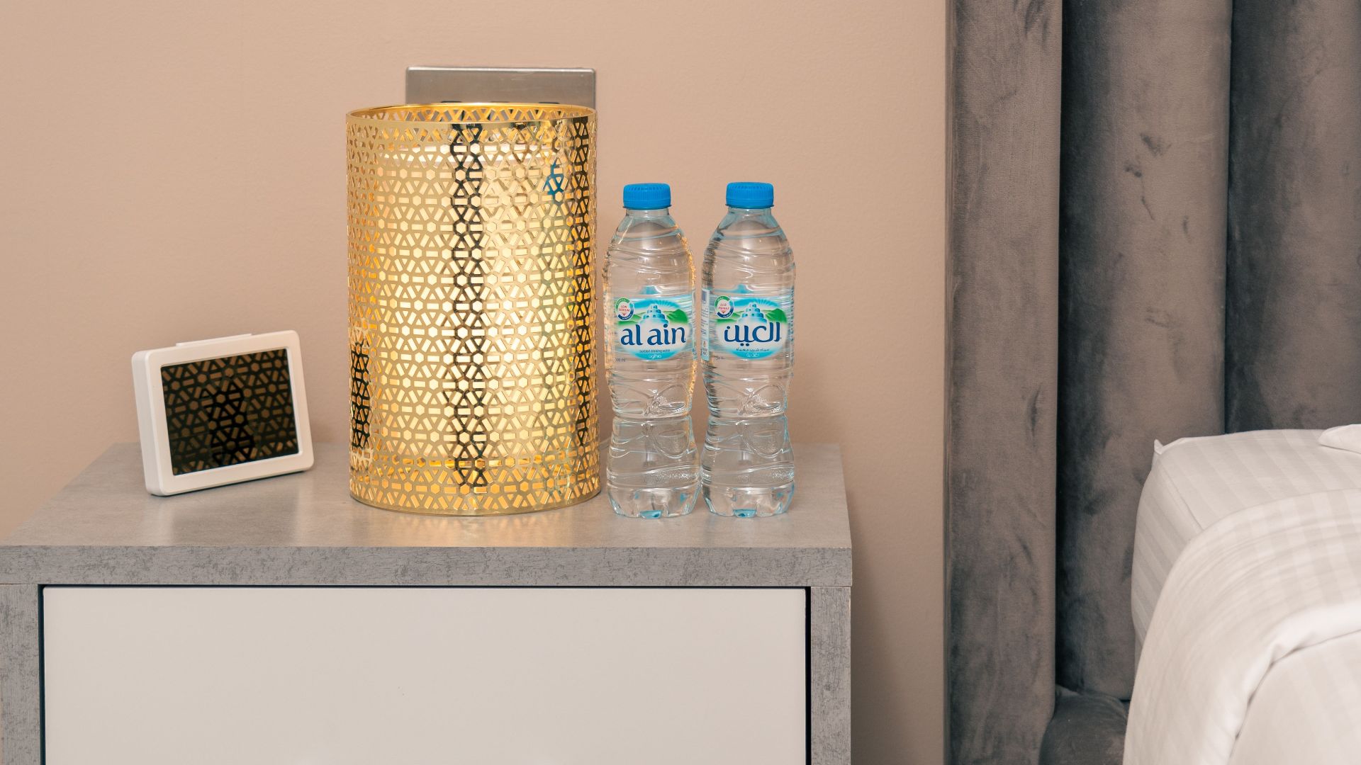 Stylish nightstand setup in a Dubai hotel room featuring a lamp, water bottles, and neat decor.