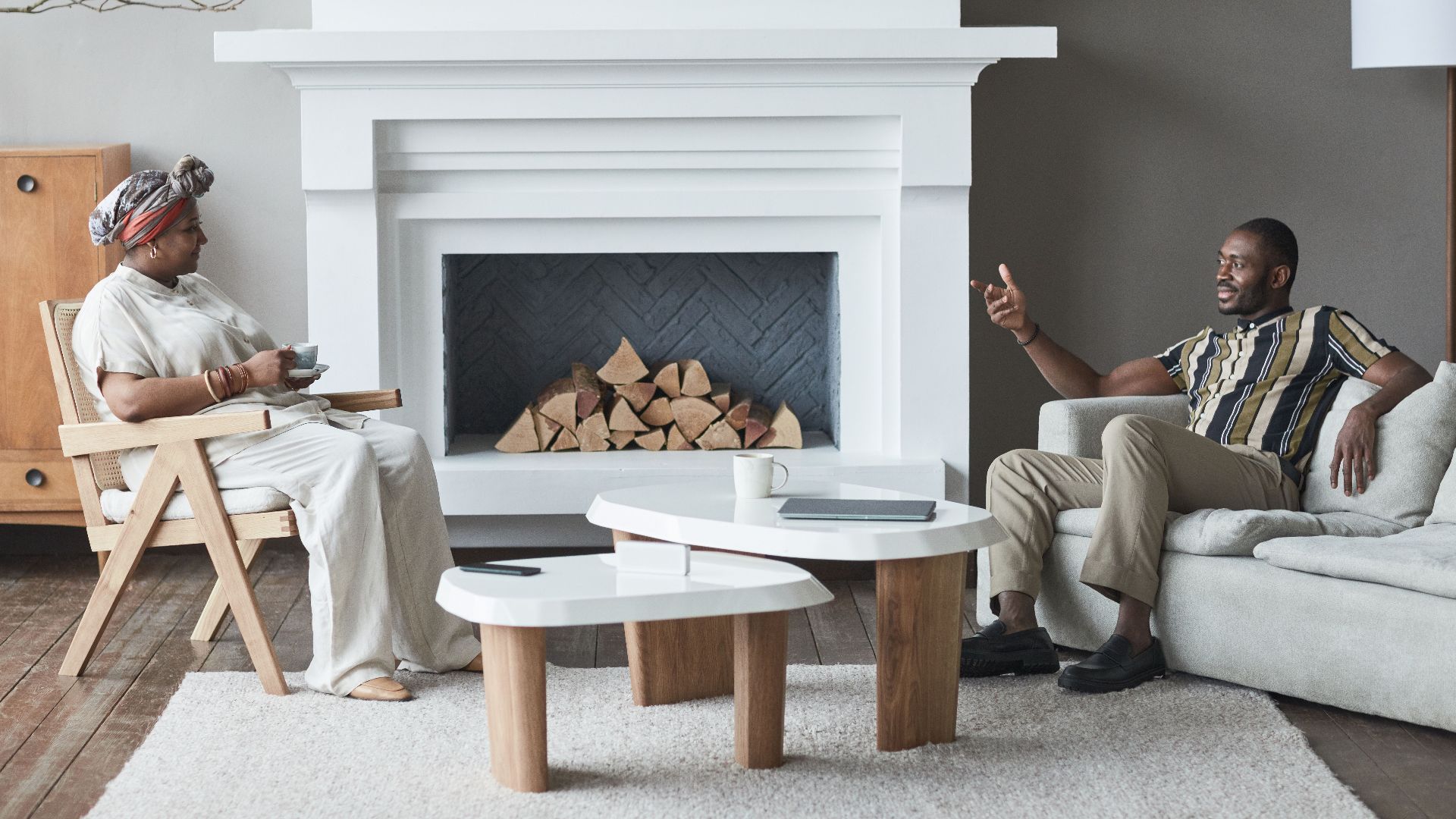 Two adults having a relaxed conversation in a stylish living room with a modern fireplace.