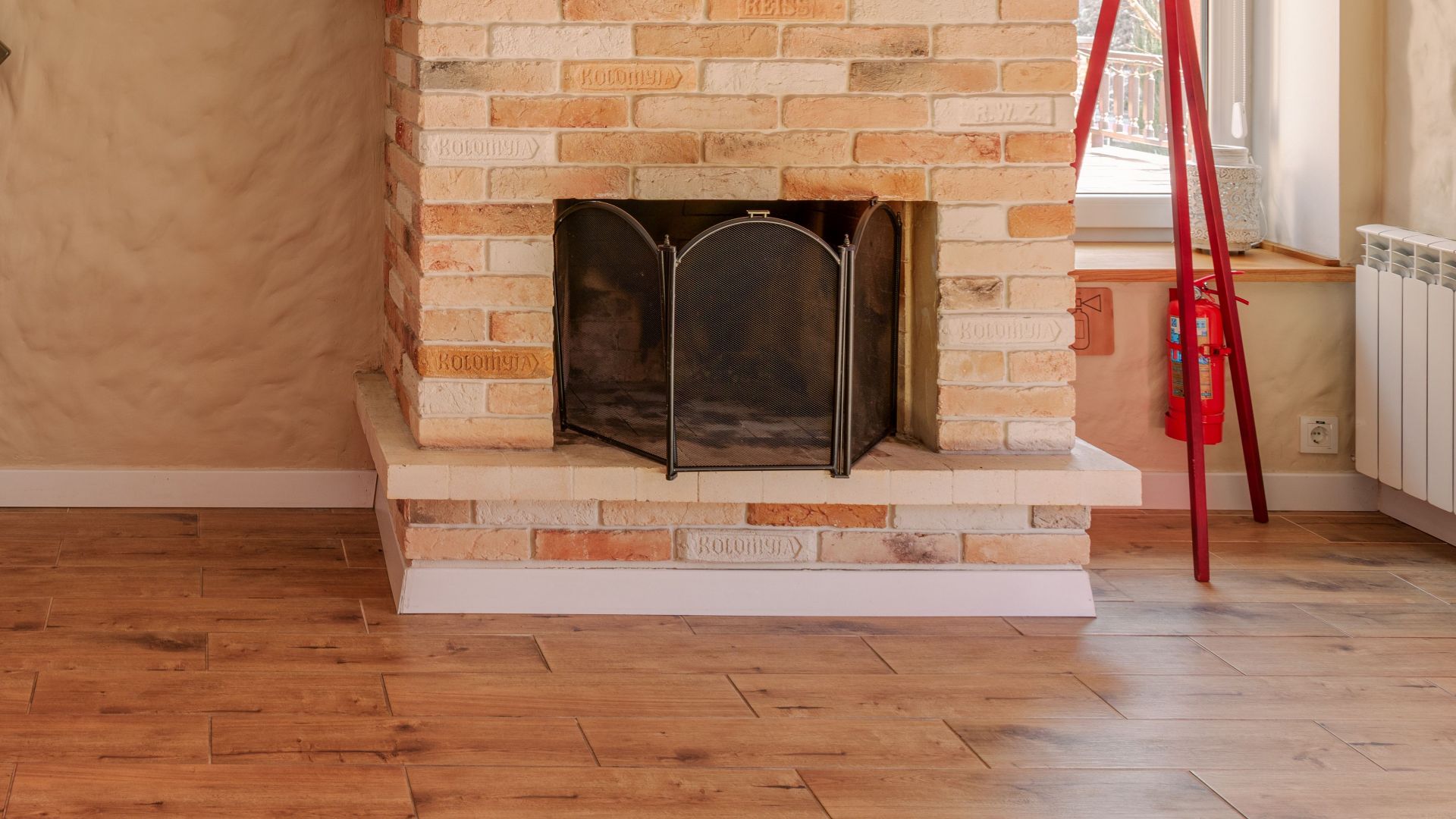 Warm rustic kitchen interior with vibrant red cabinets and a charming brick fireplace for a cozy home feel.