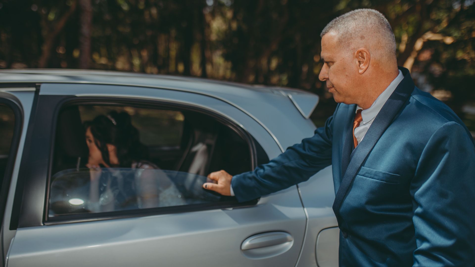 Formal wedding arrival with a bride in a car and an elegantly dressed man opening the door.