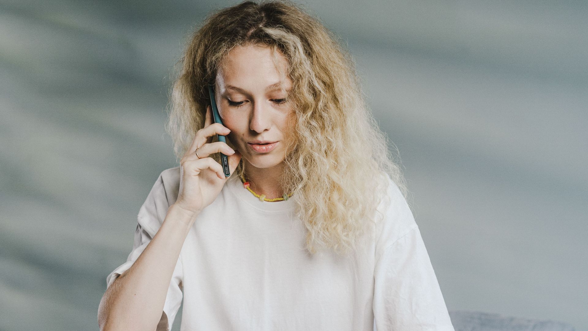 Young woman multitasking at home on laptop and phone call.