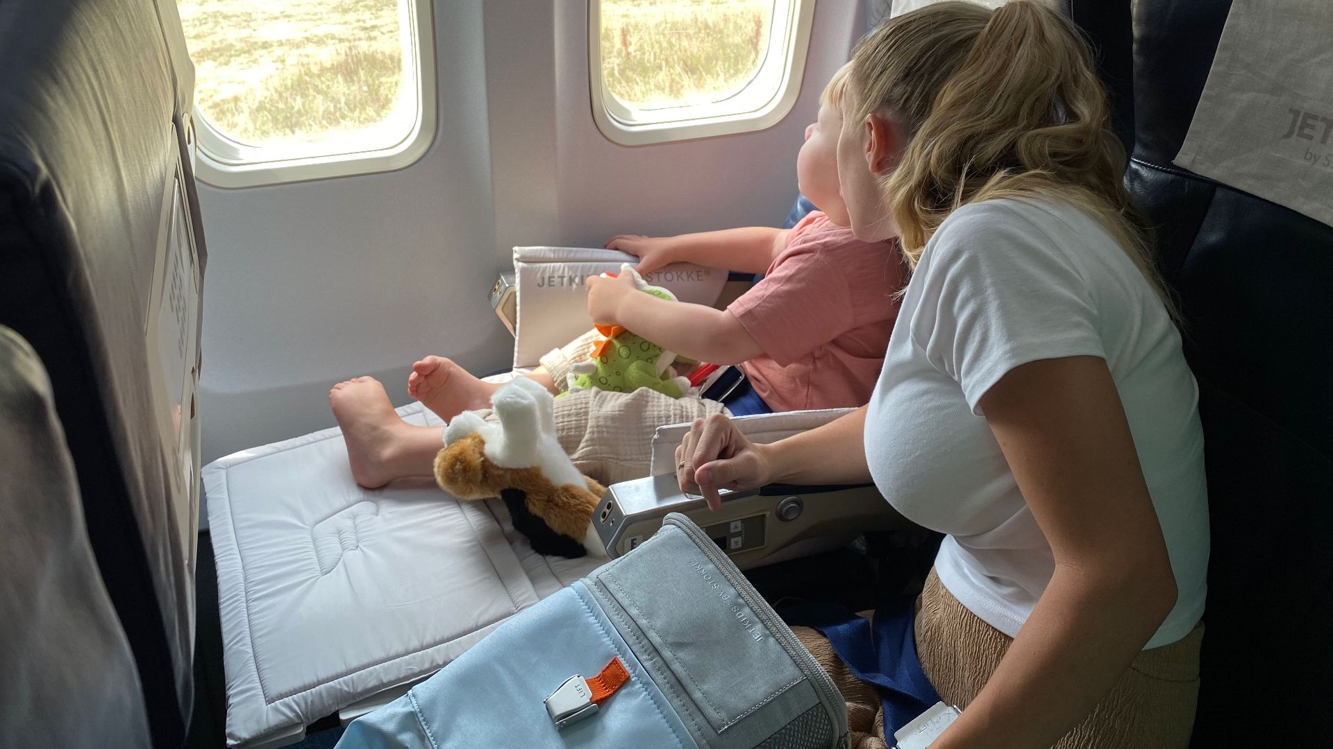Mother and child sitting inside airplane, enjoying scenic view through windows during flight travel.