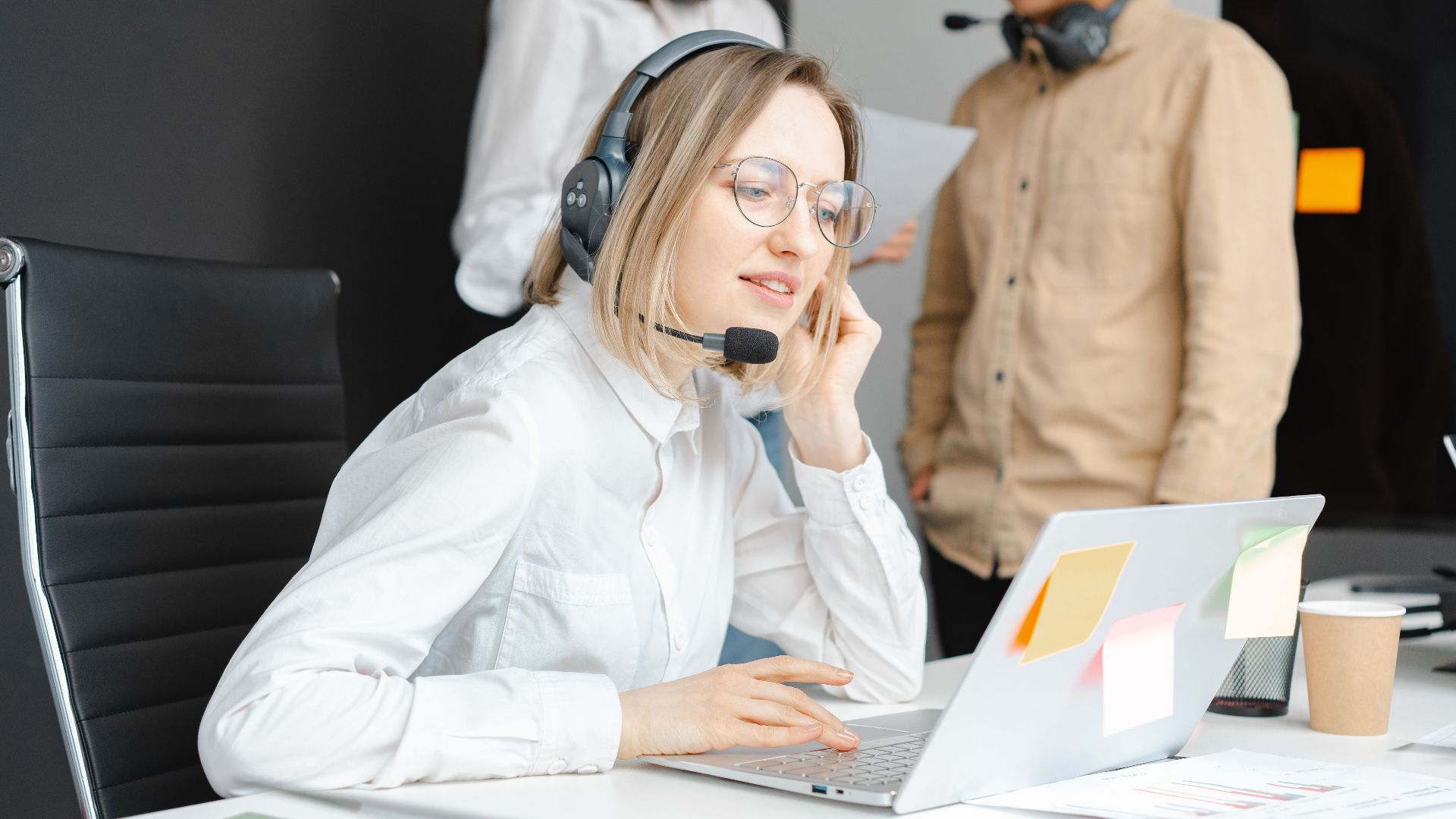 Customer support professionals working with headsets and laptops in a modern office environment.