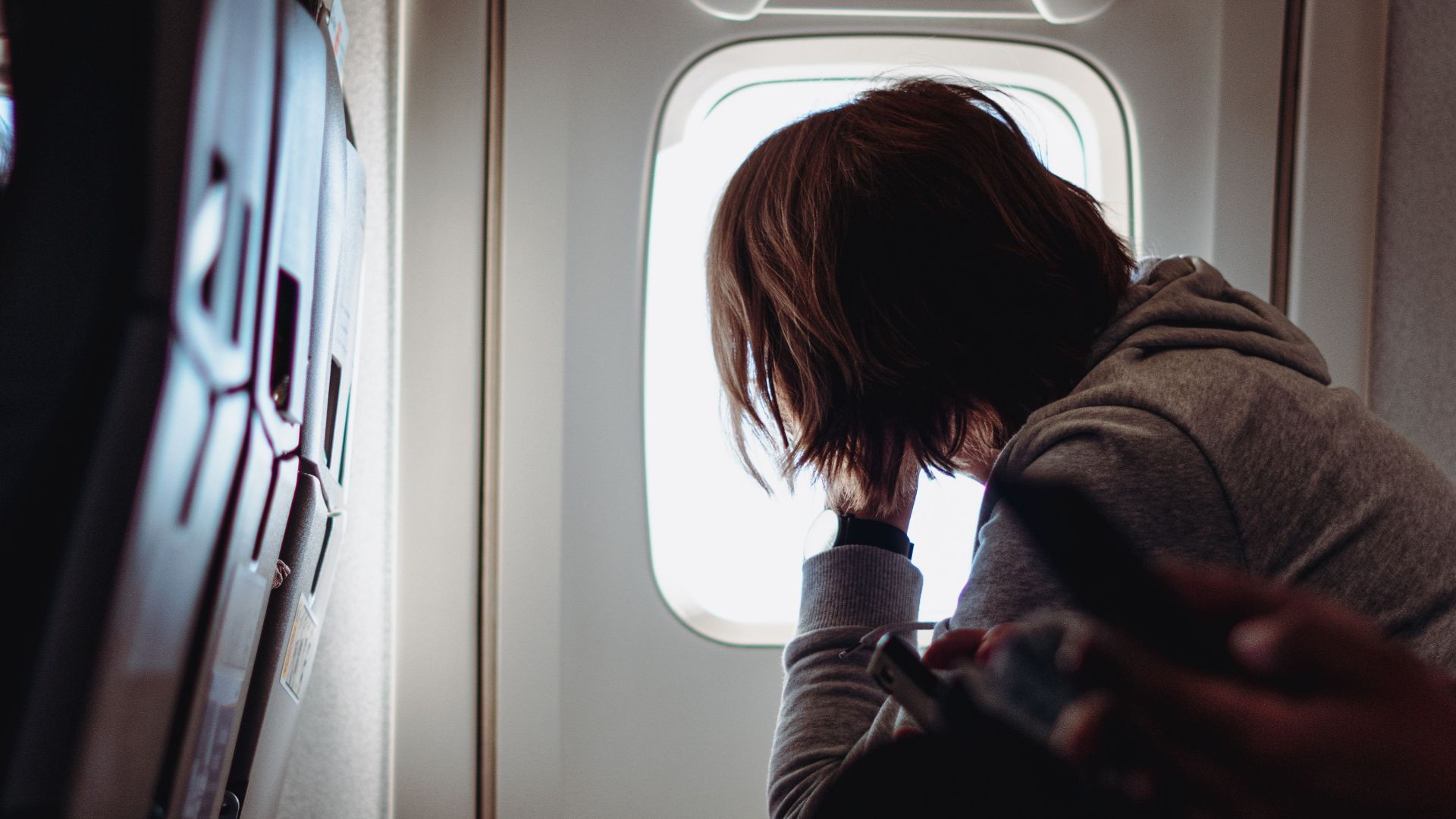 A passenger gazes out of an airplane window, reflecting on in-flight travel.