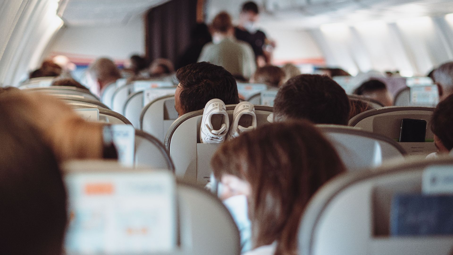 View of passengers wearing masks and seated in economy class during flight.