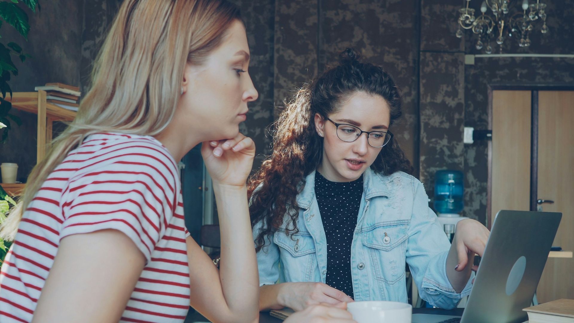 Two women discuss something on a laptop