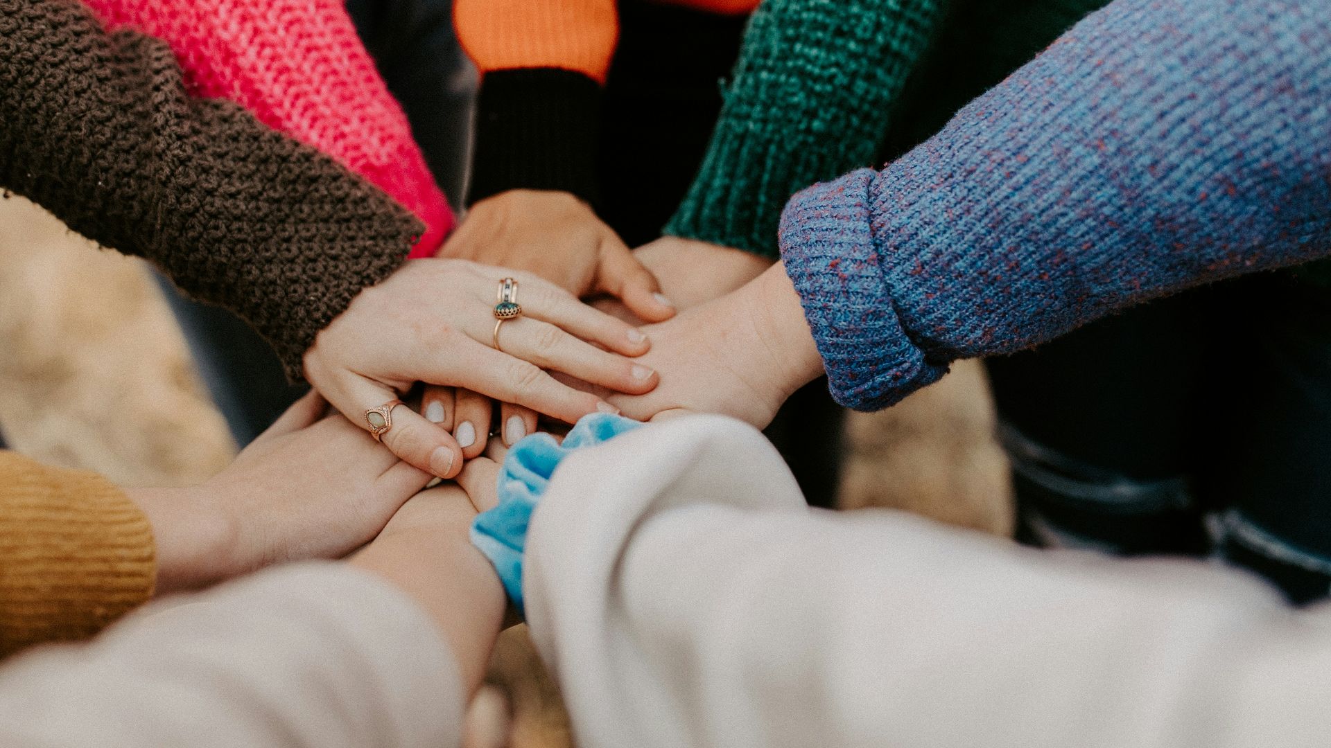 group stacking hands in colorful sweaters