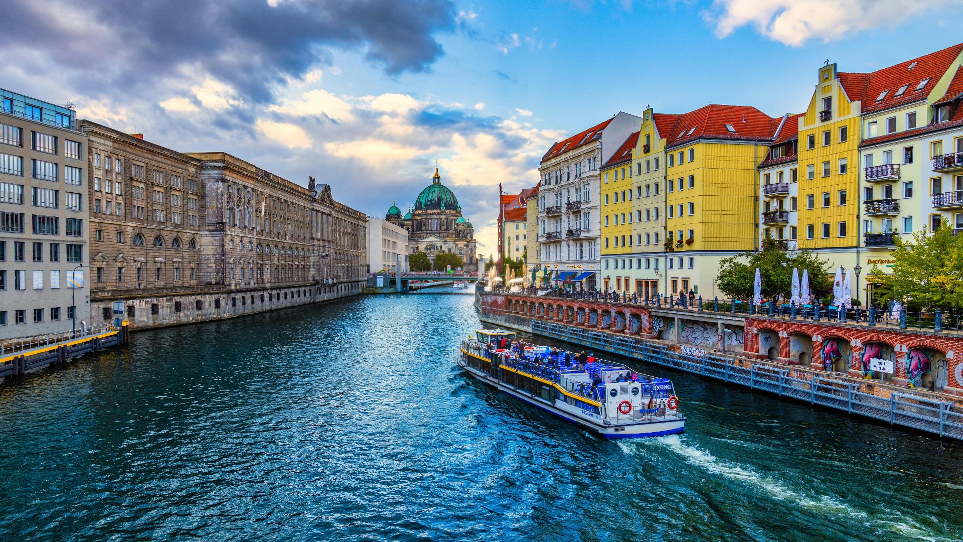 A boat navigates a river through a vibrant european city