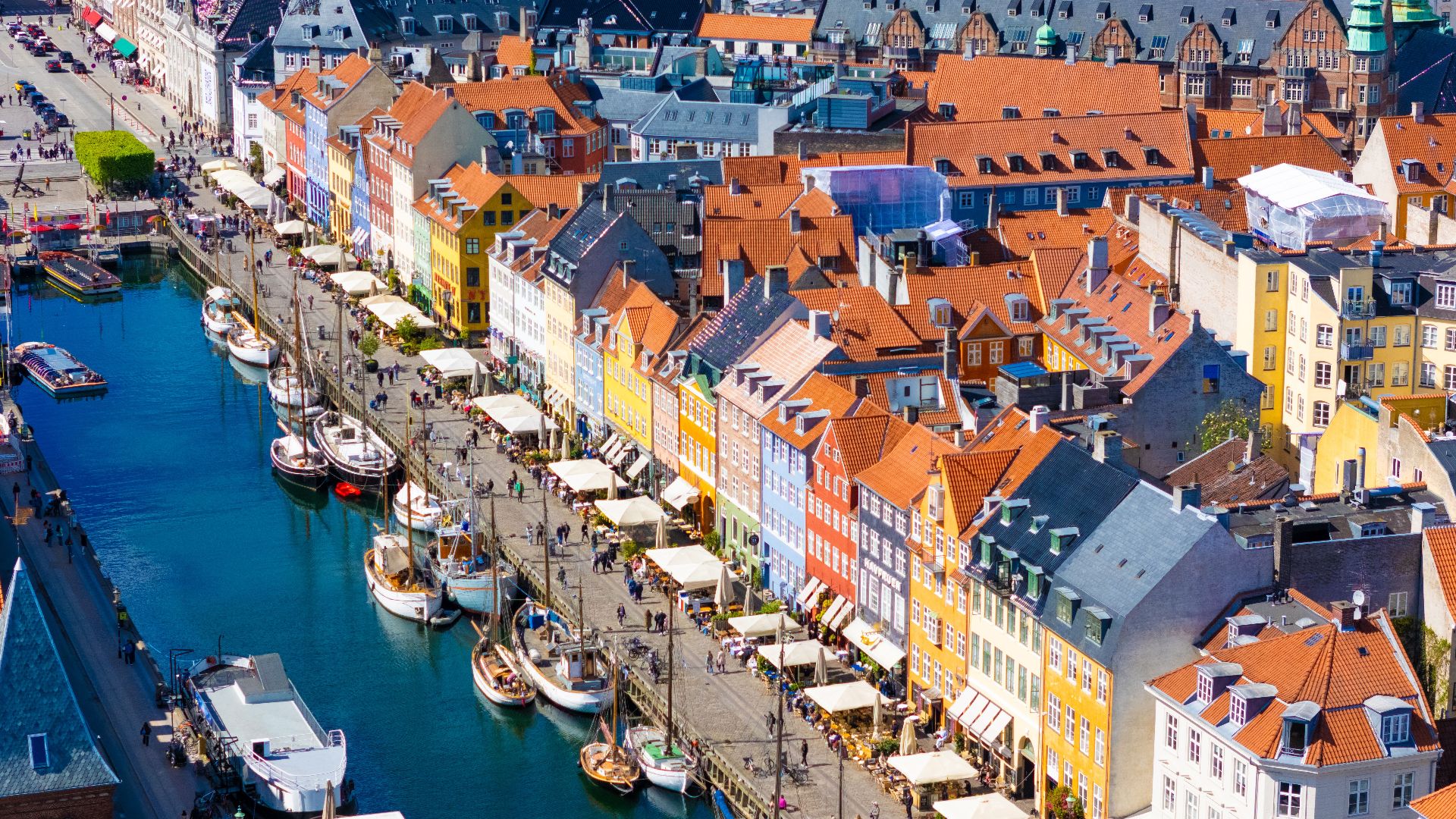 Vibrant aerial view of Nyhavn Canal in Copenhagen, showcasing colorful buildings and historic boats.