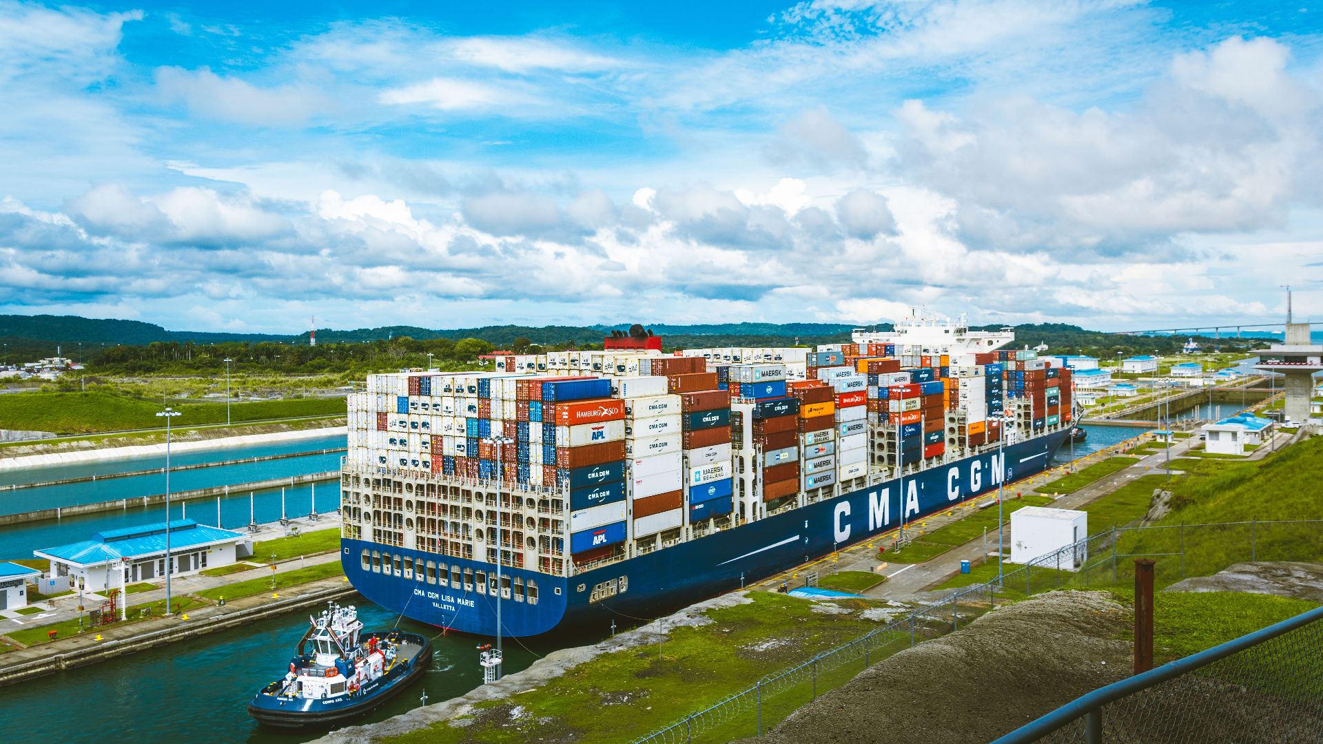 A vast cargo ship passes through the Panama Canal on a bright day, showcasing global trade.