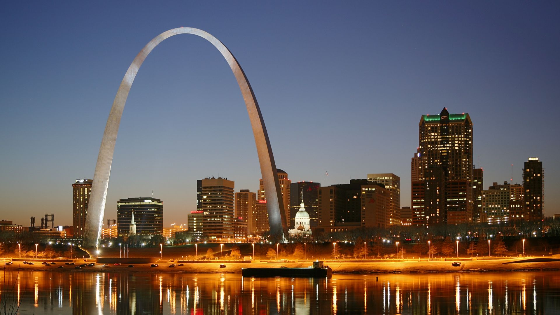 St. Louis on the Mississippi river by night. Jefferson National Expansion Memorial aka. Gateway Arch and Old Courthouse are visible.