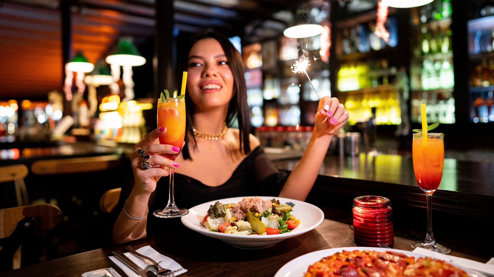Woman enjoying a festive dinner with cocktails in a lively Istanbul restaurant.