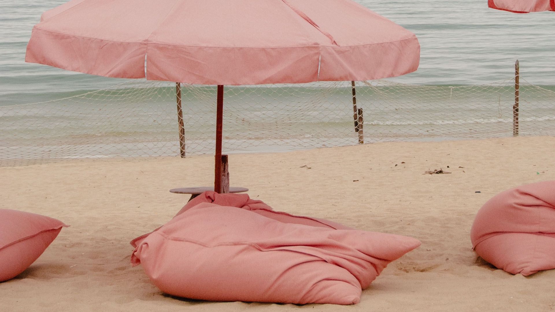 Serene beach scene with pink umbrellas and bean bags by the sea.