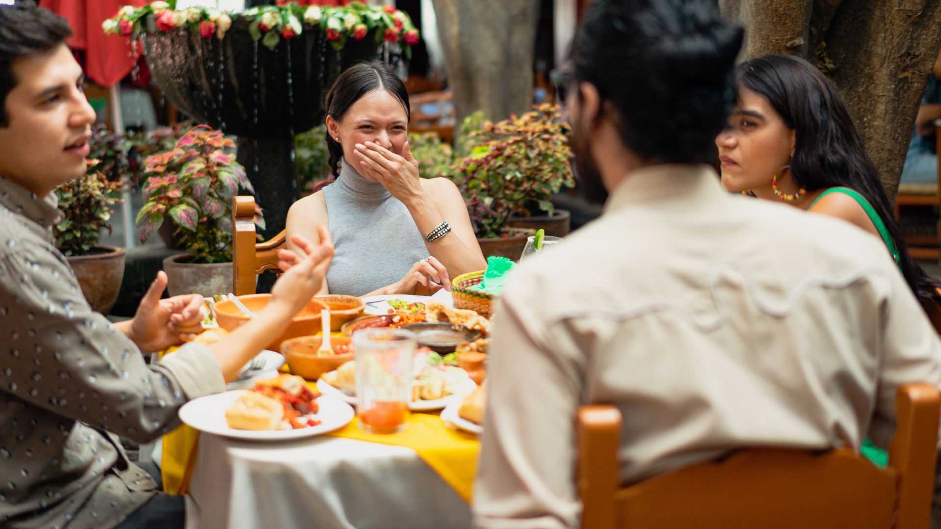 Group of friends enjoying Mexican food at an outdoor restaurant with laughter and smiles.