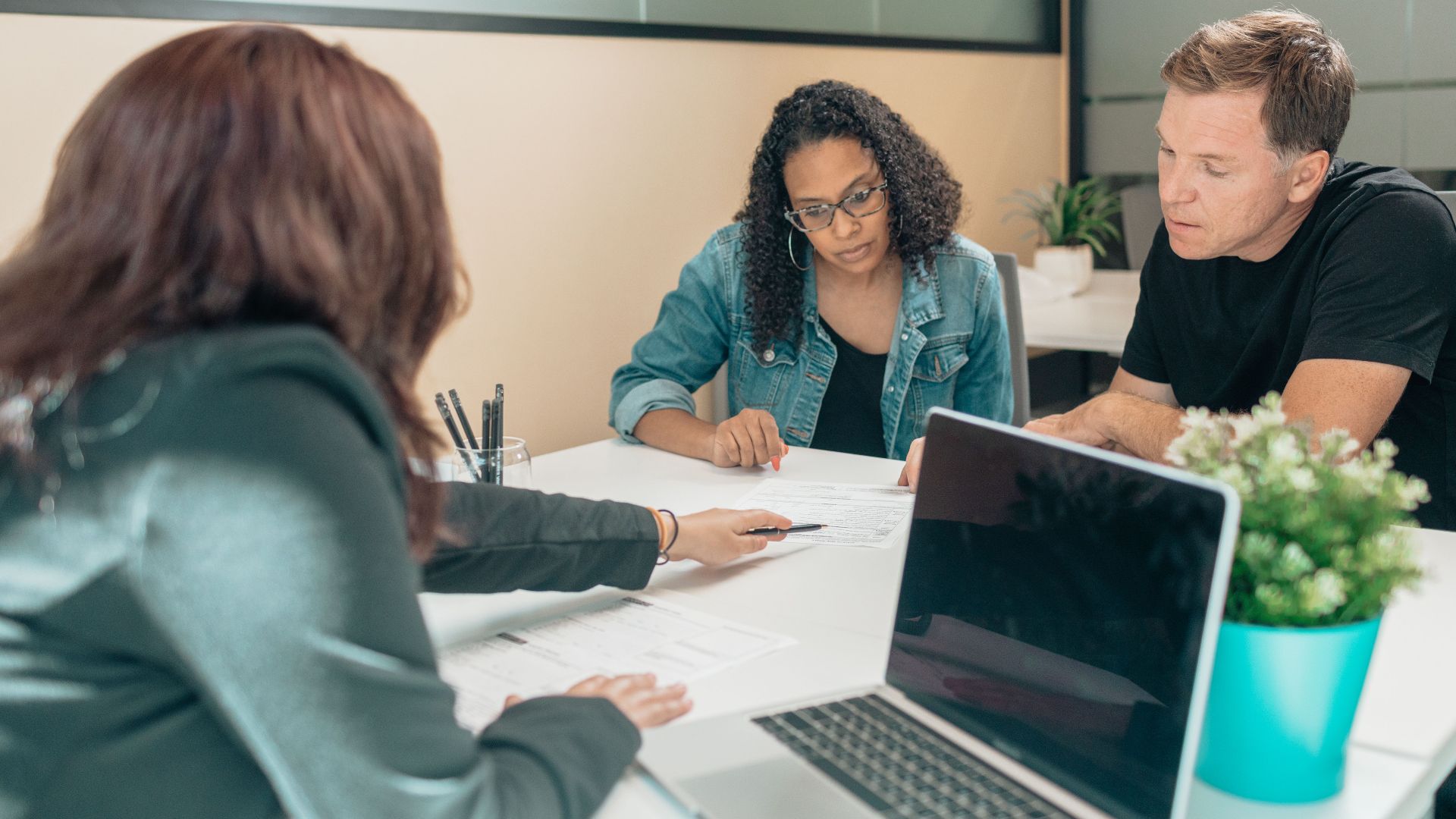 Couple meeting with advisor for adoption process in a modern office setting.