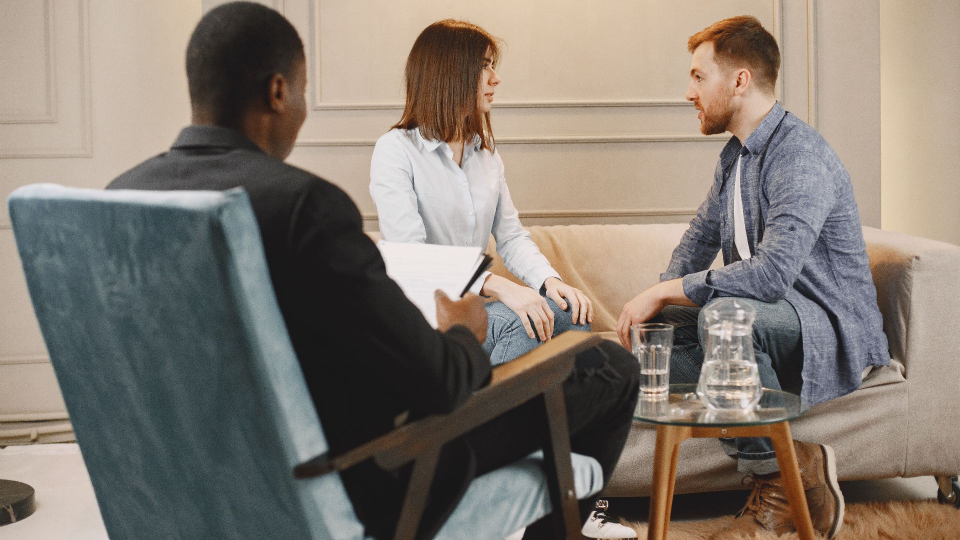 Couple in a counseling session with a therapist in a modern and cozy setting.