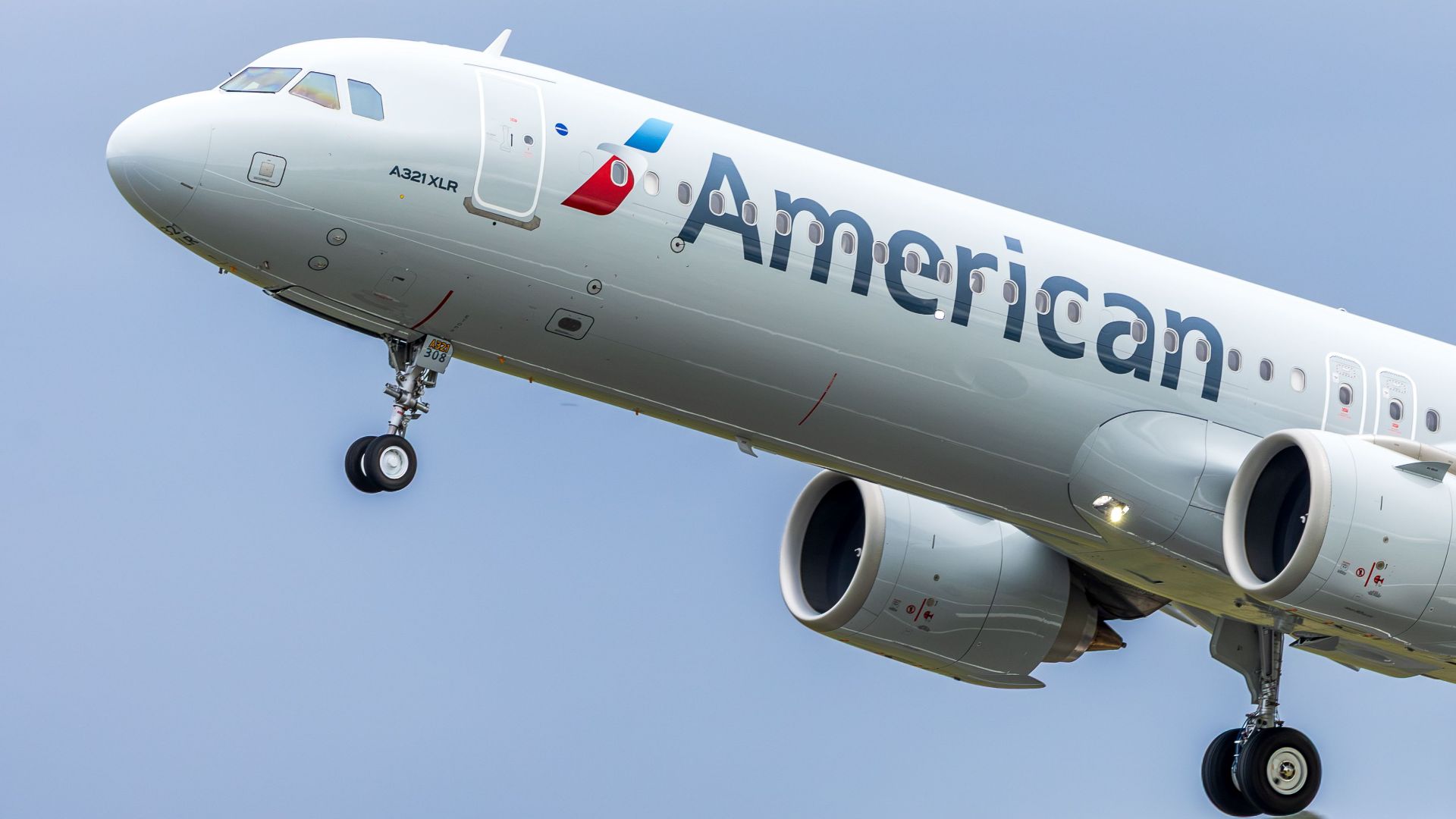 American Airlines A321XLR airplane ascending against a clear sky in Scotland.
