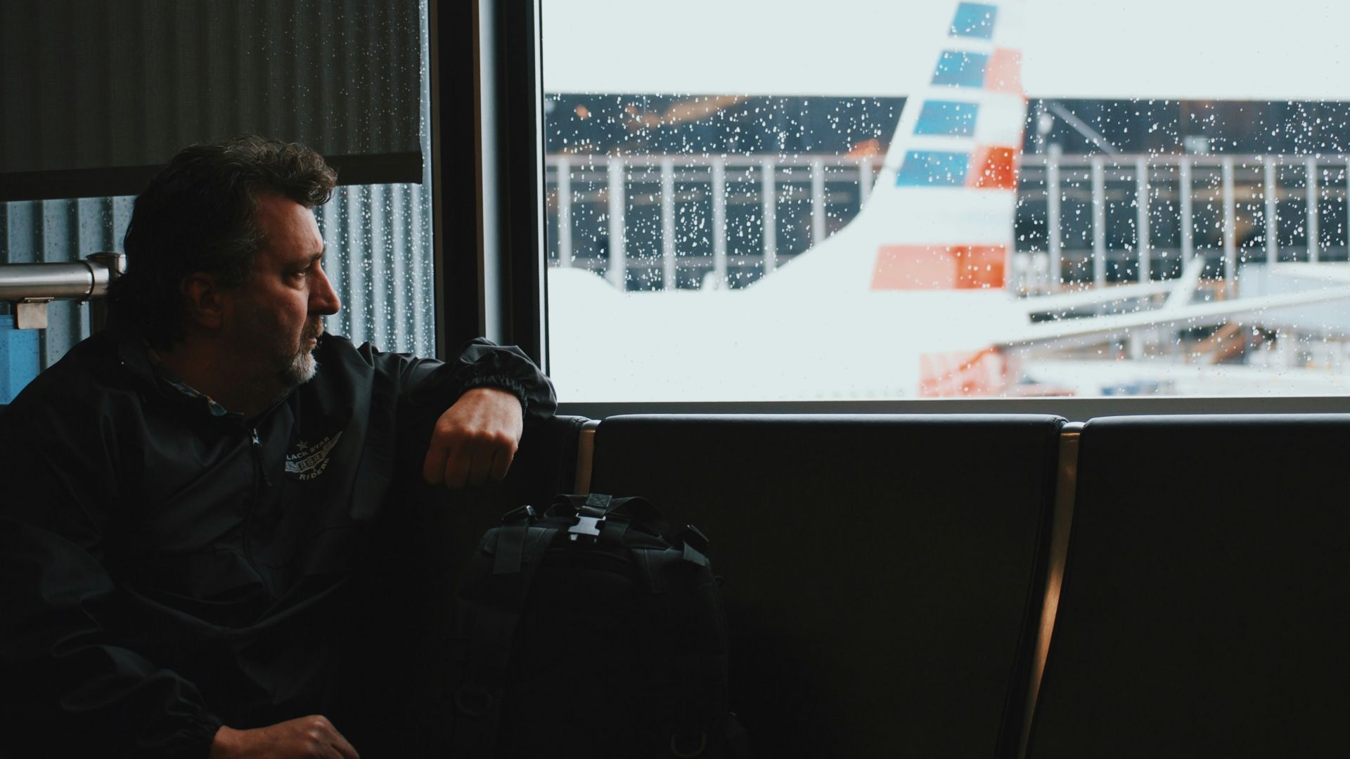 man sitting in airport watching airplane during daytime