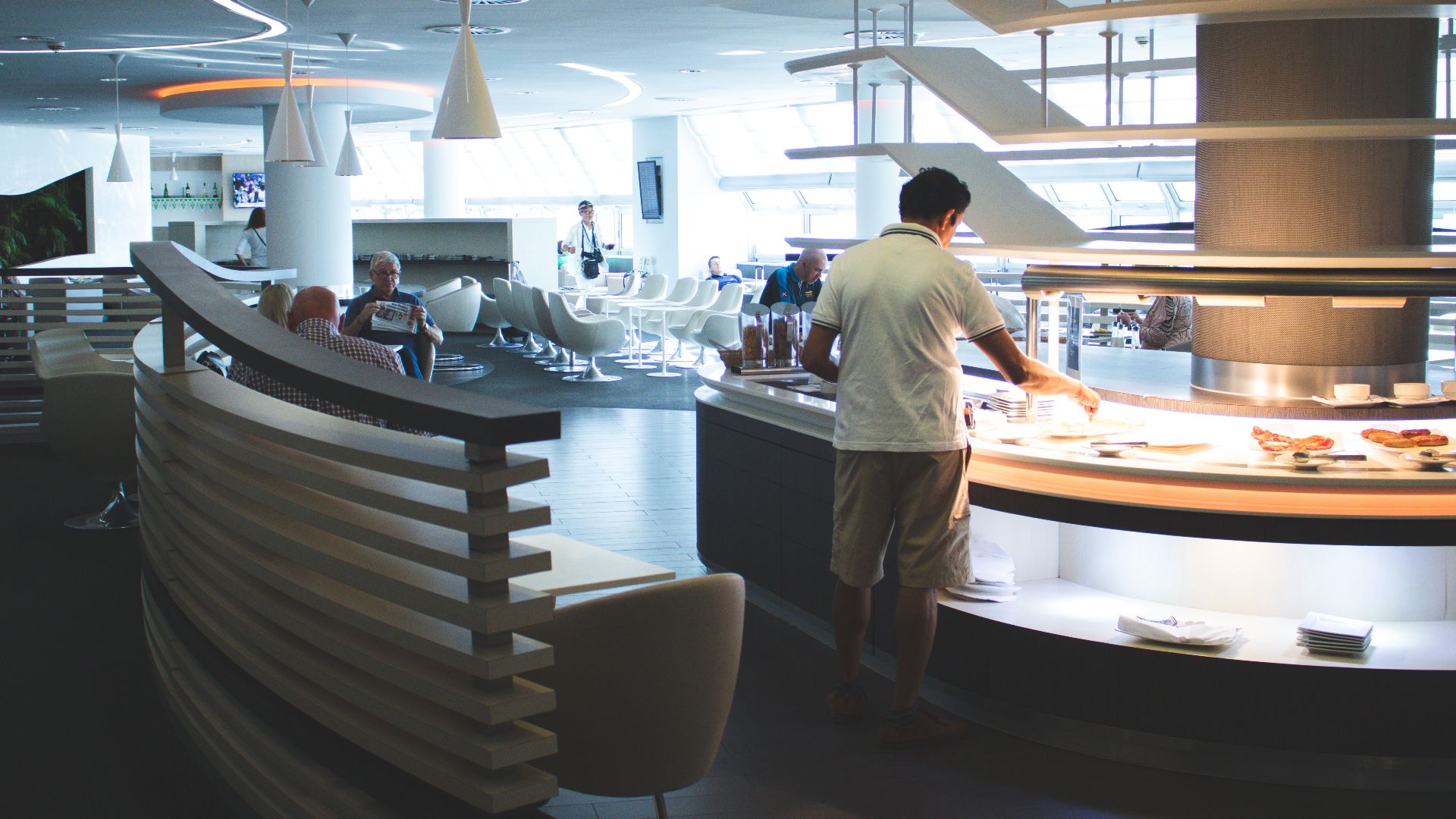 Stylish airport lounge with buffet and seating, featuring sleek interior design and contemporary furniture.