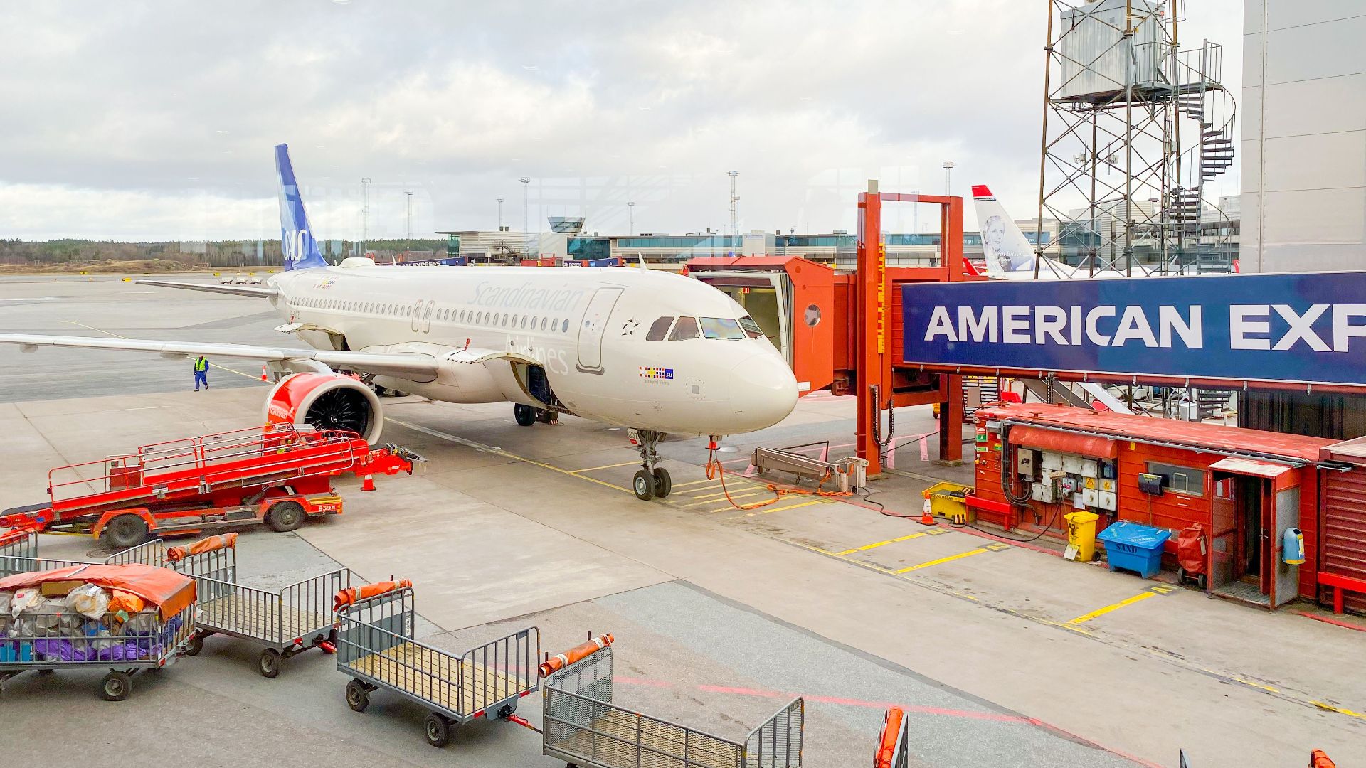 Aircraft docked at Stockholm Arlanda Airport gate with ground crew and equipment.