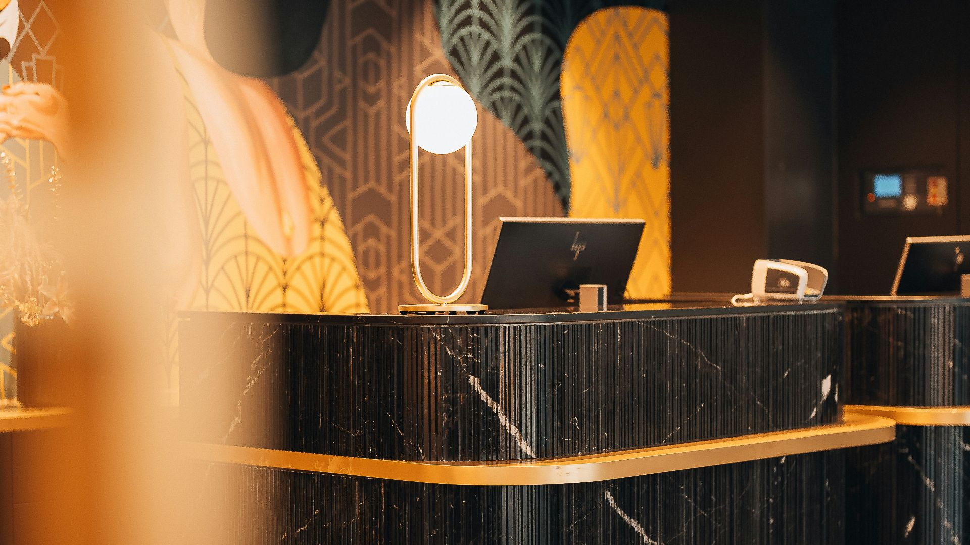 A black marble reception desk with gold trim in a hotel lobby