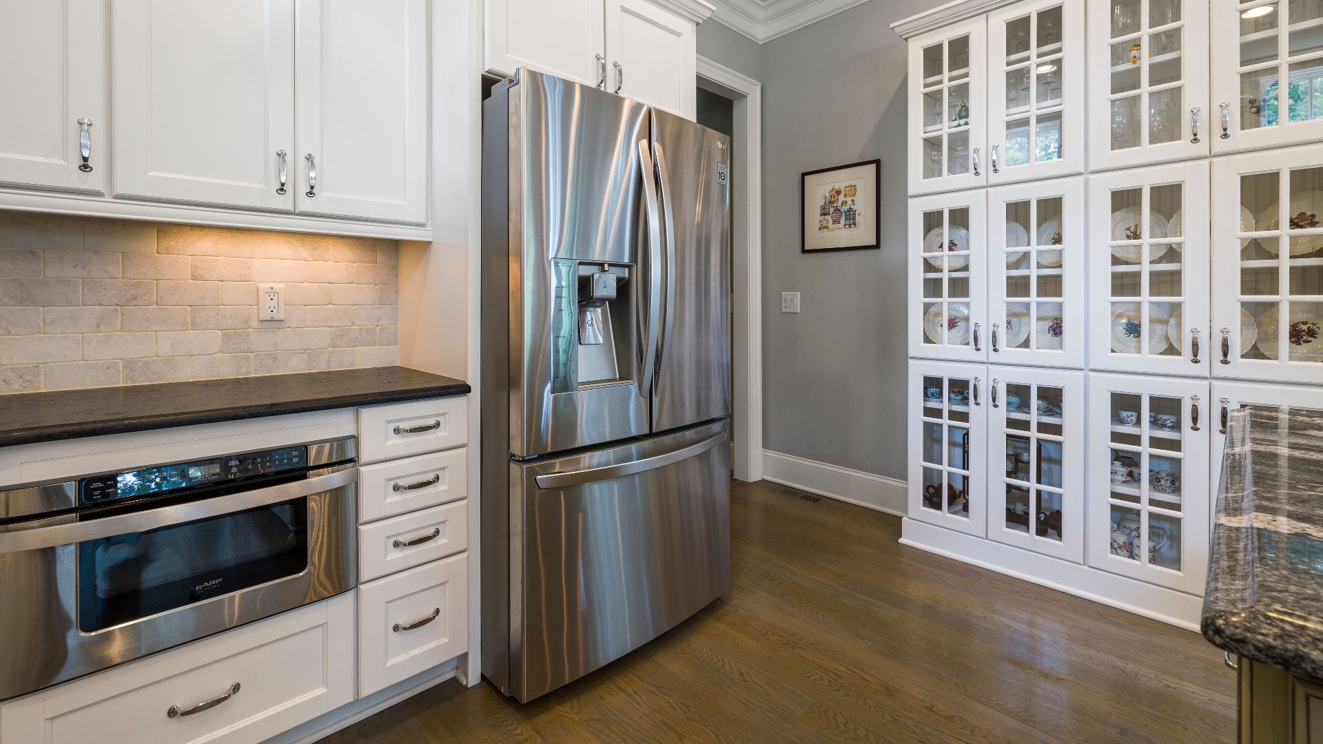 Contemporary kitchen interior featuring stainless steel fridge and white cabinets.