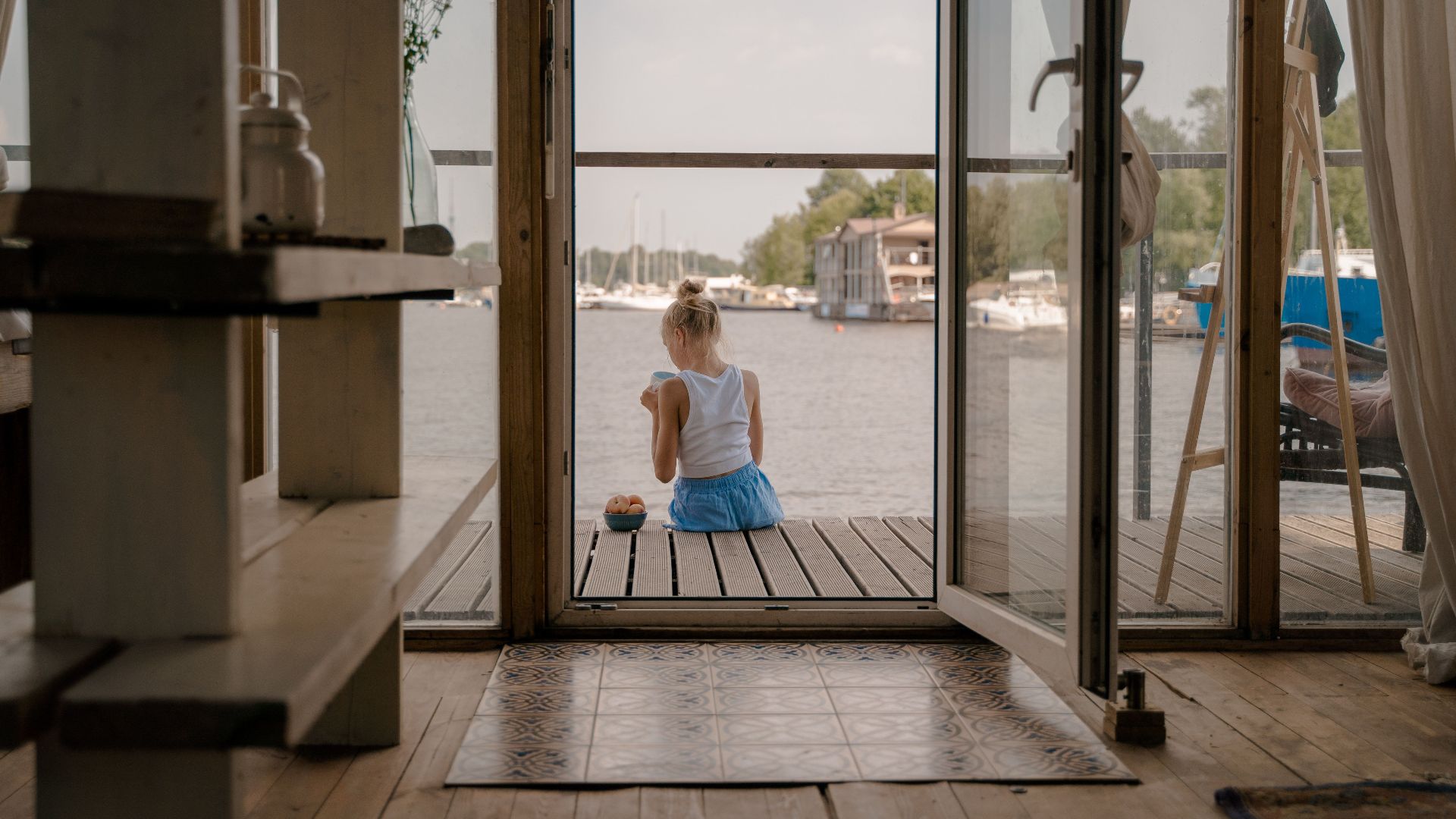 Woman sitting on a deck, gazing at waterfront view, exuding tranquility.