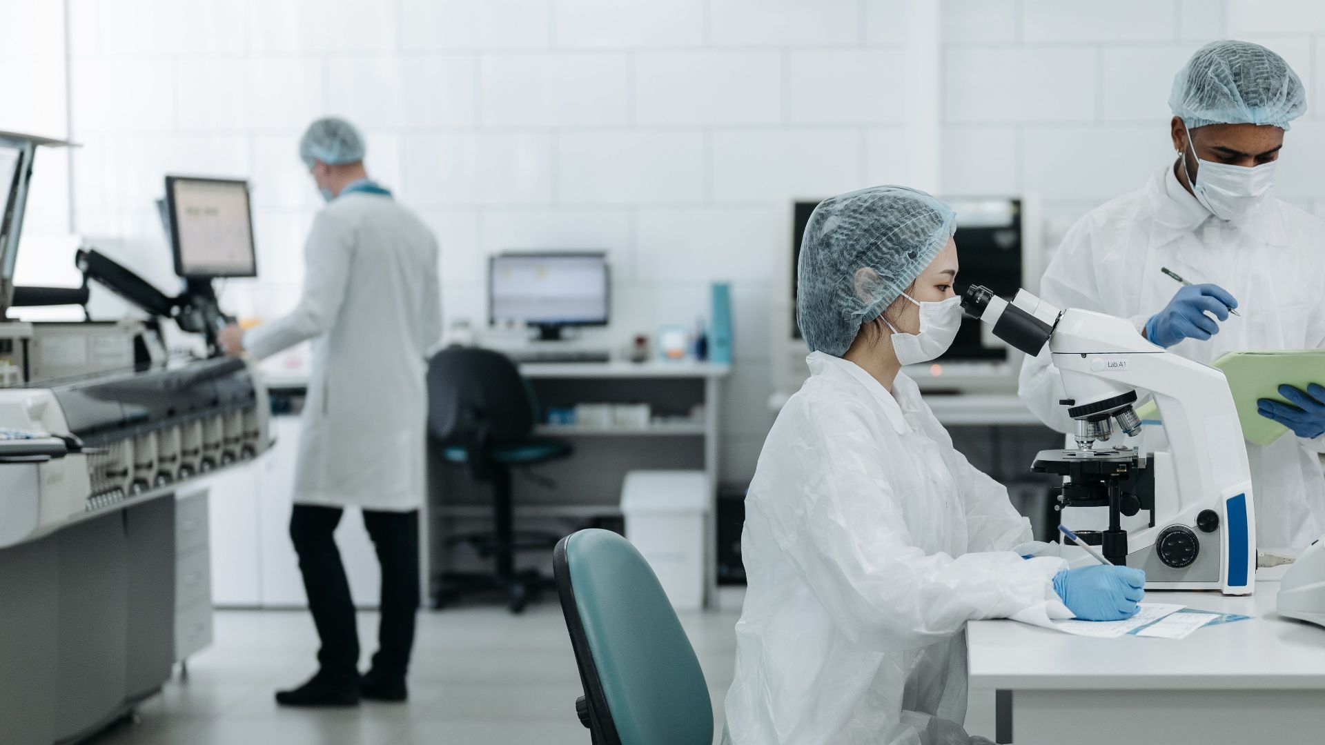 Researchers in protective gear examining samples in a state-of-the-art laboratory setting.