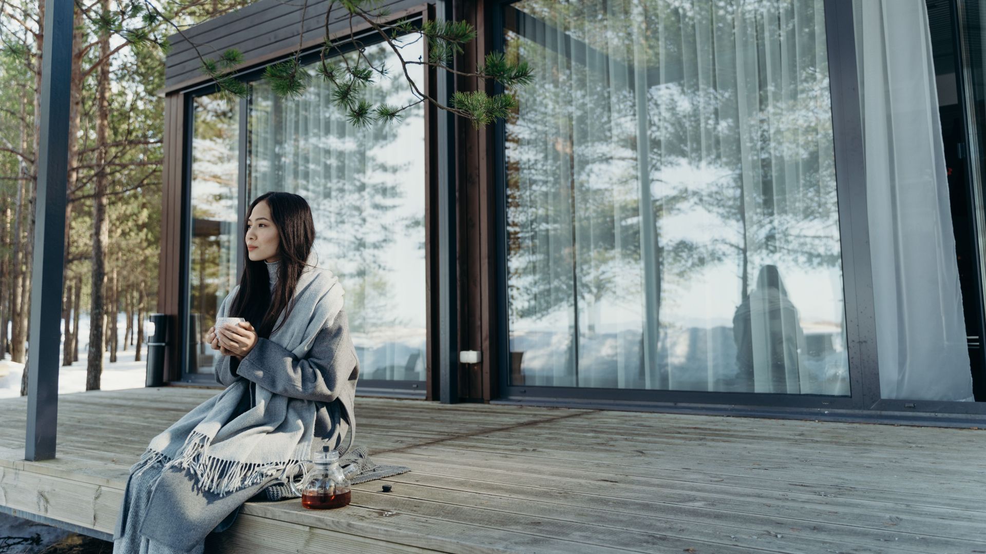 Asian woman enjoying a hot drink on a peaceful winter morning outdoors.