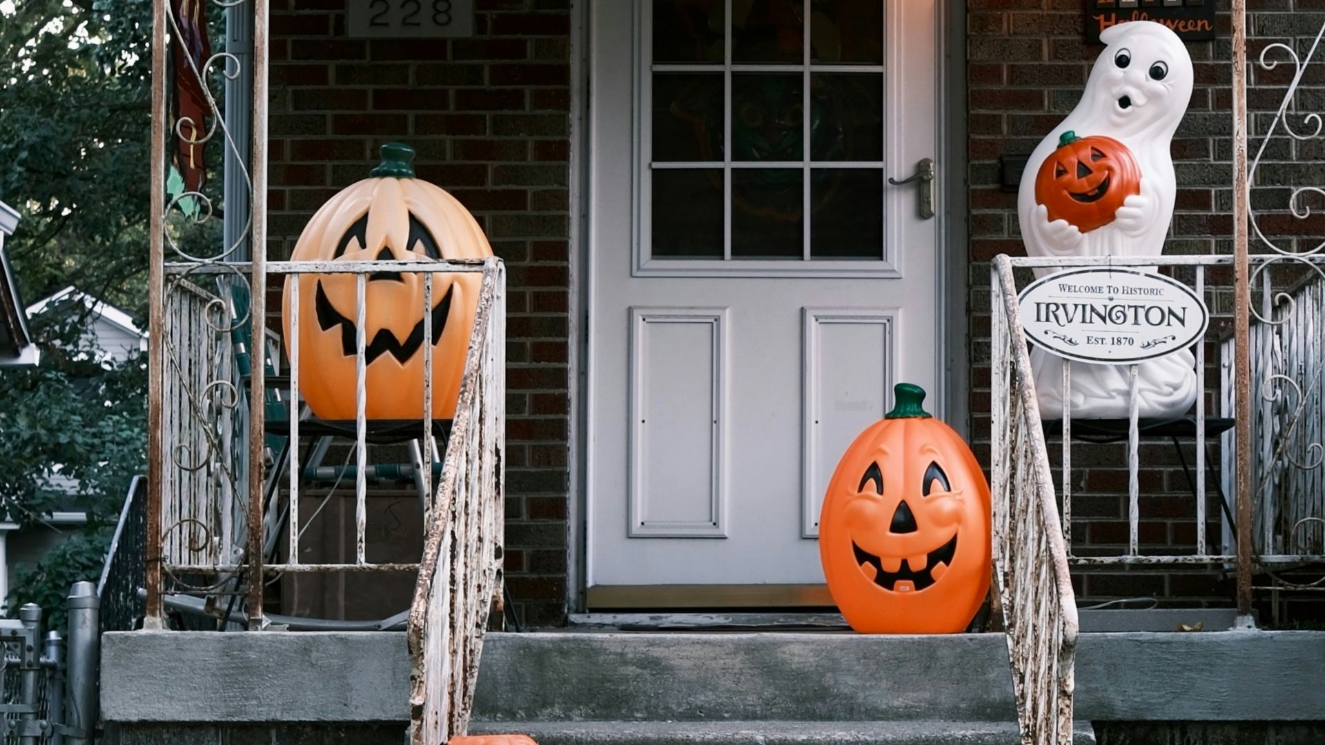 Halloween decorations on a house porch with pumpkins and ghosts
