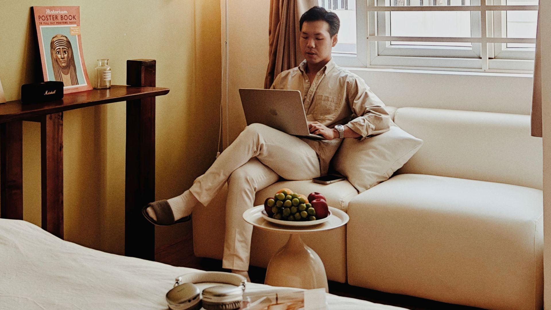 A cozy Airbnb room in Vietnam with a man relaxing and working on a laptop, creating a serene atmosphere.