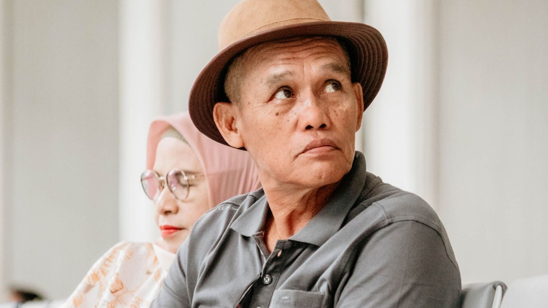 An elderly Asian couple patiently waiting at an airport lounge, conveying travel anticipation.
