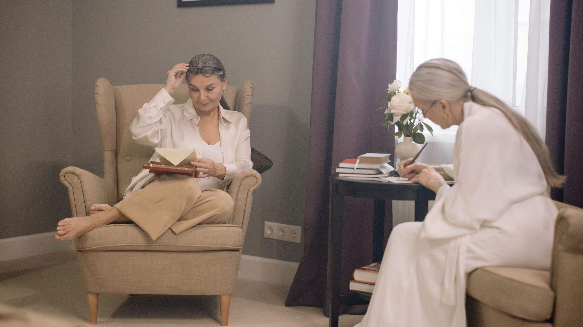 Two senior women enjoying a relaxing afternoon, reading and writing indoors.