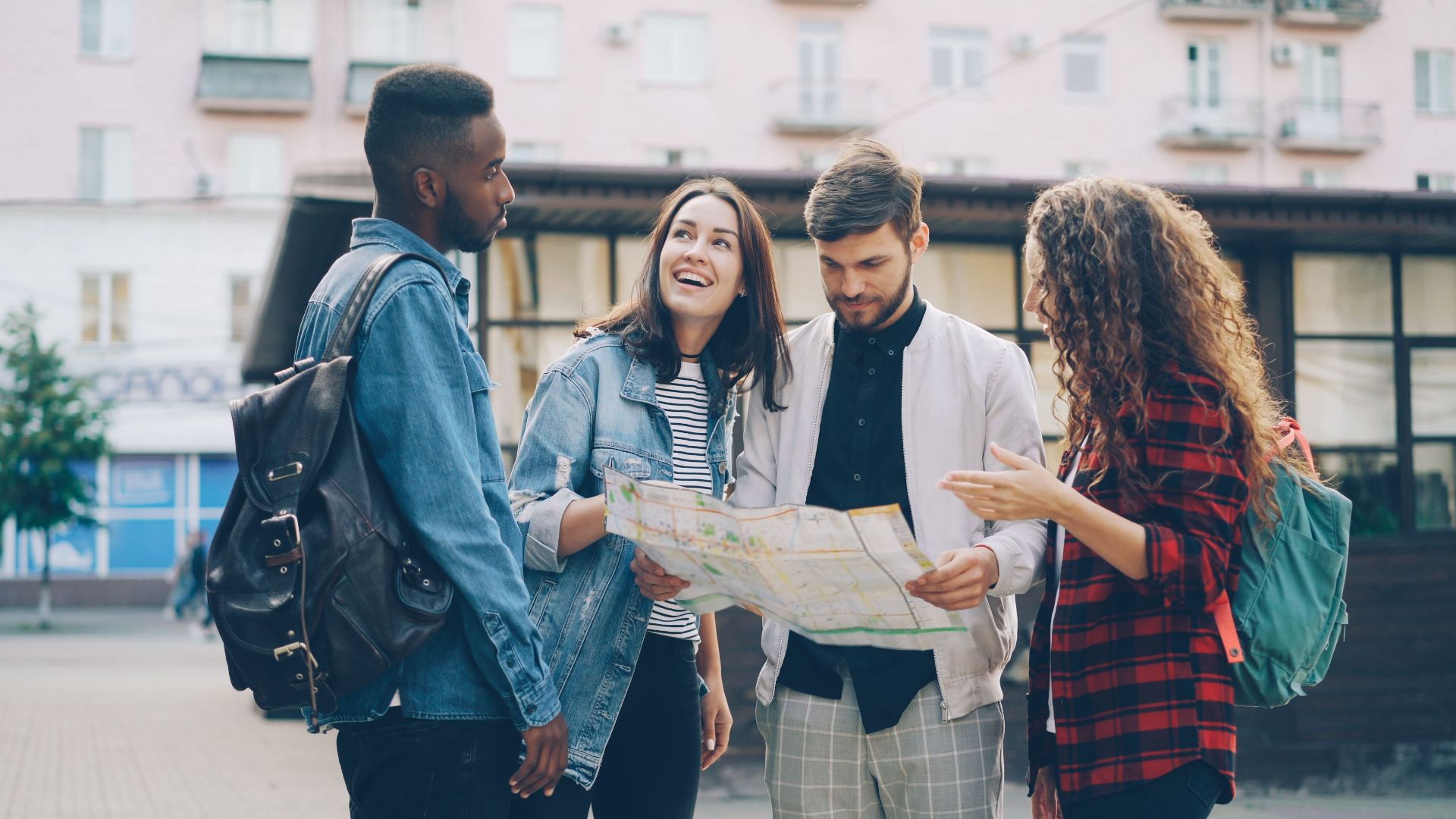 Four young friends reading a map outdoors, planning their city adventure.
