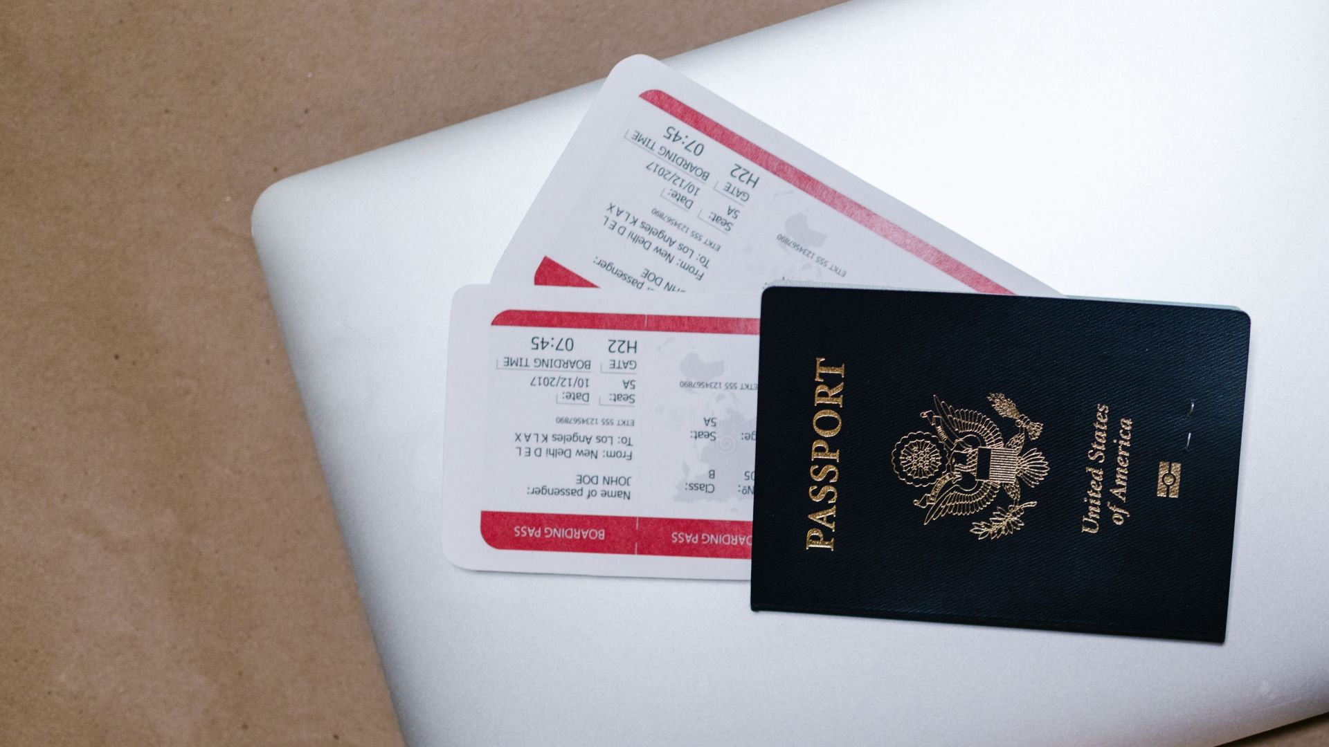 Close-up of a passport and boarding passes on a laptop, symbolizing travel preparation.