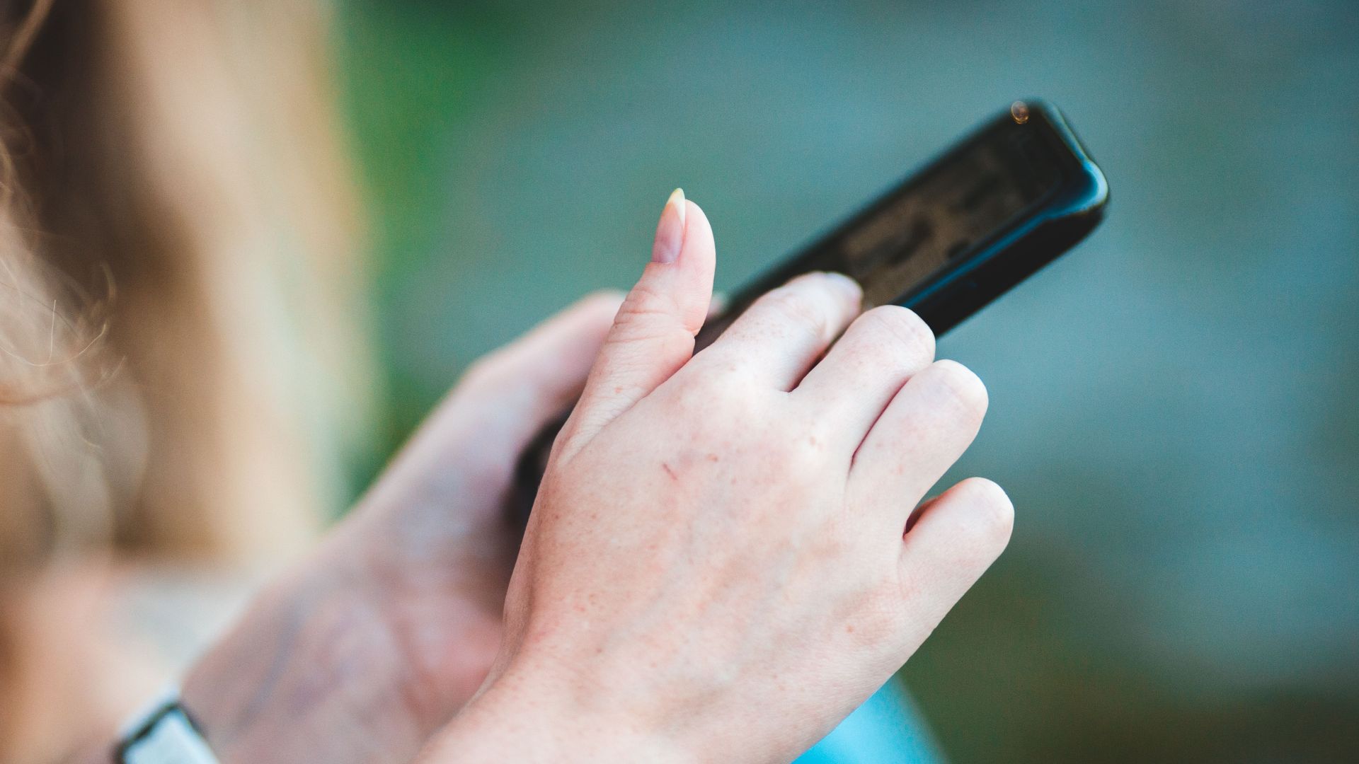 Hands holding a smartphone with blurred background, showcasing modern technology use.