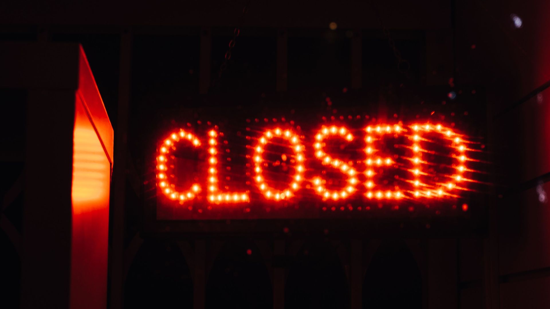 Bright red neon closed sign illuminating a dark space, conveying closure and night ambiance.