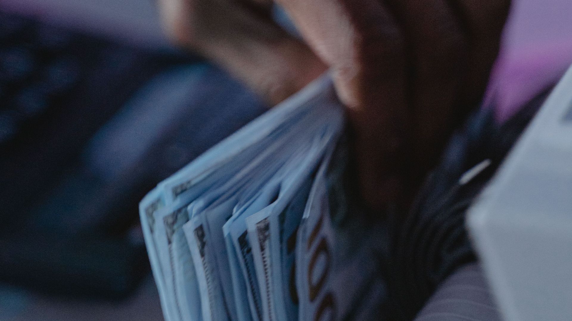 A close-up of a hand using a cash counter machine to sort bills.