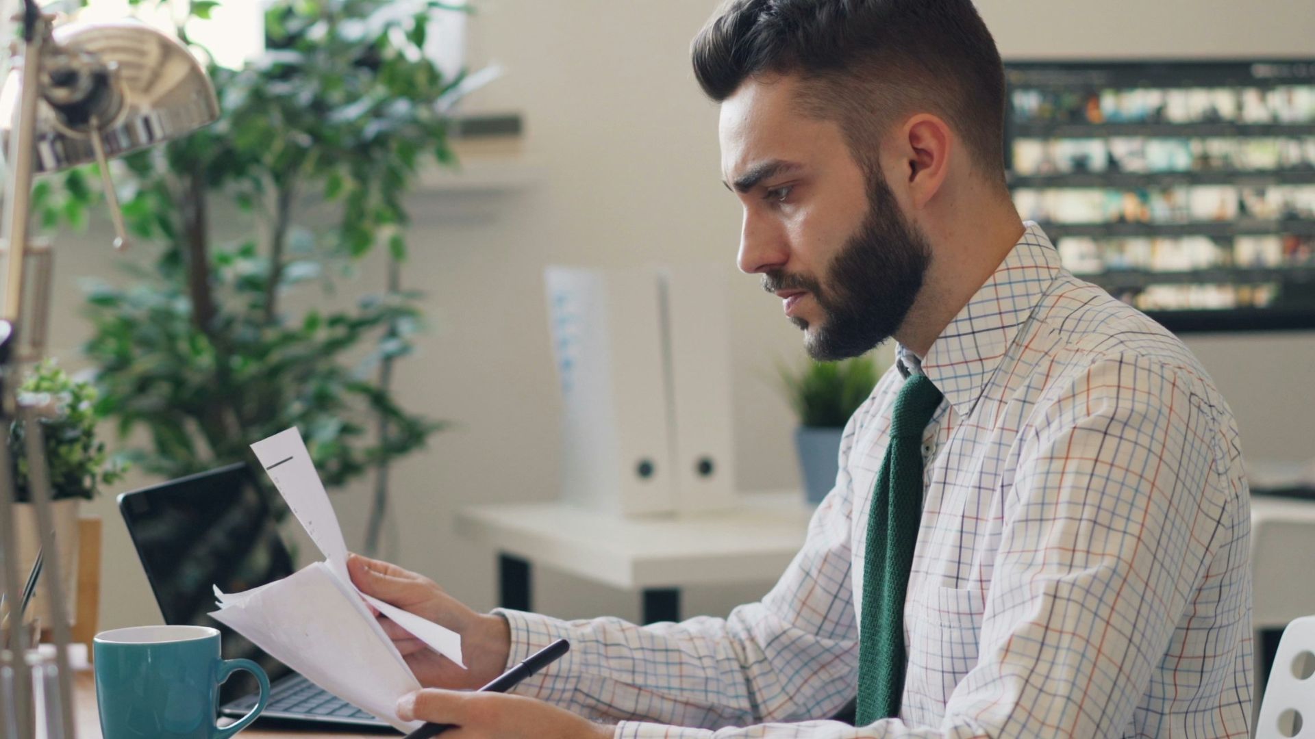 a man sitting at a desk with a laptop and papers