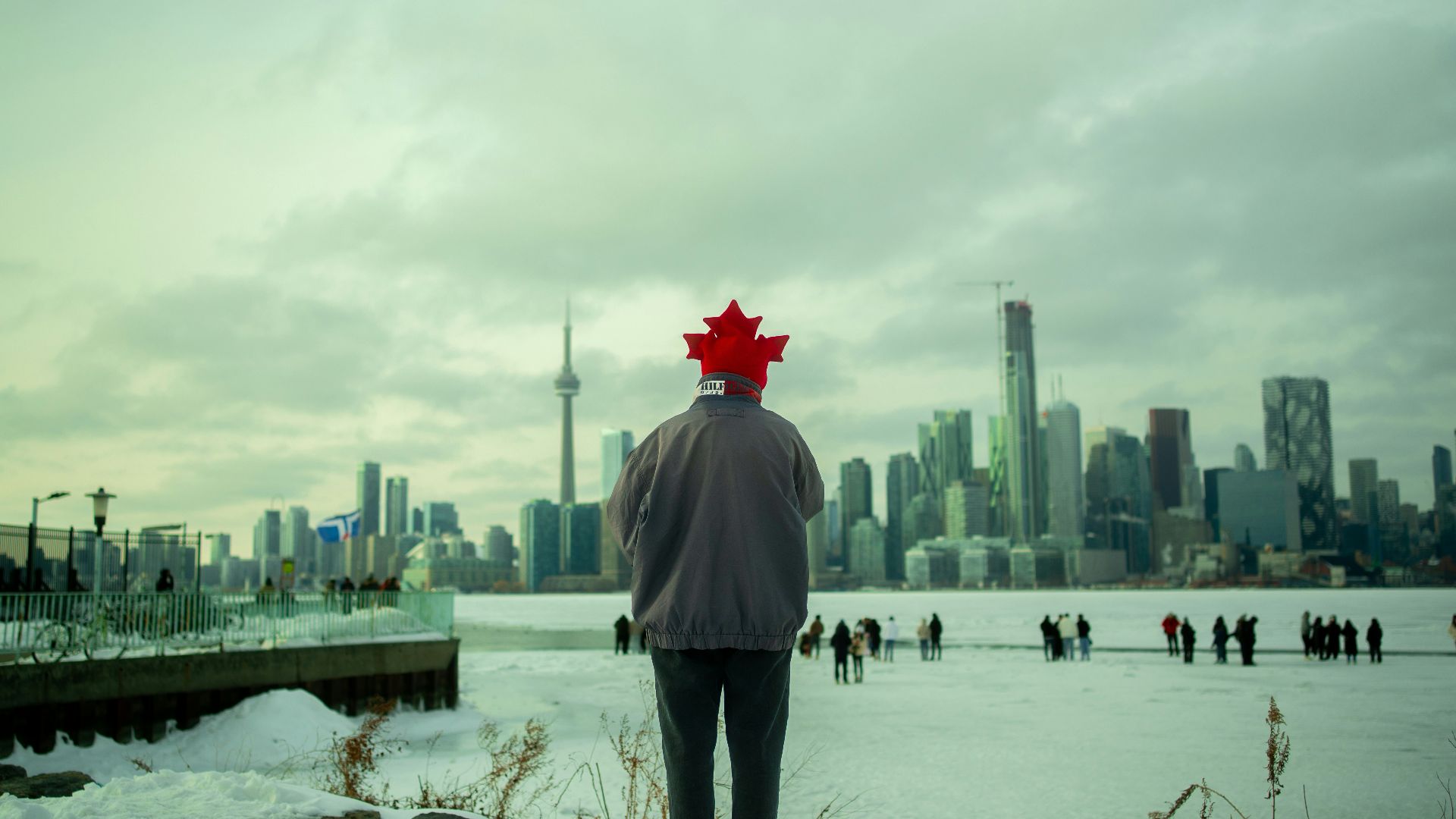 Man with canadian flag hat overlooks toronto skyline