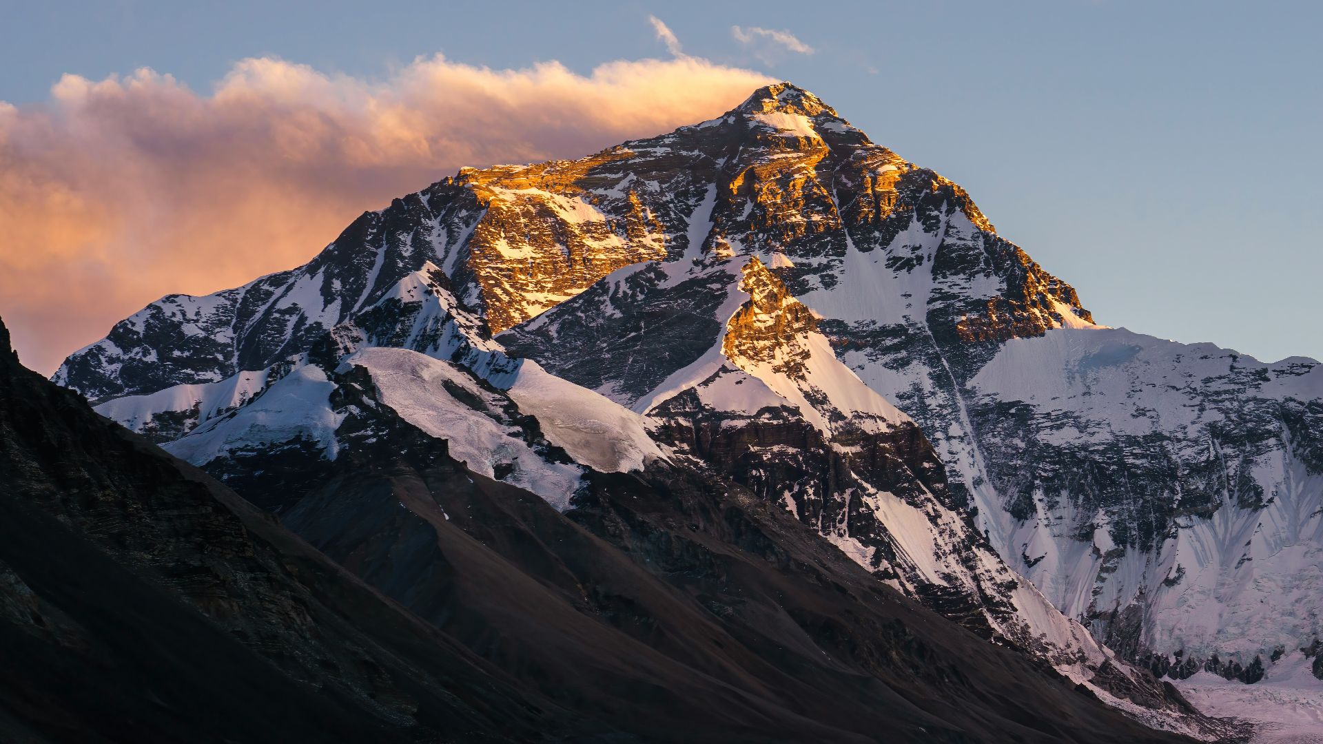 a snow covered mountain with clouds in the sky