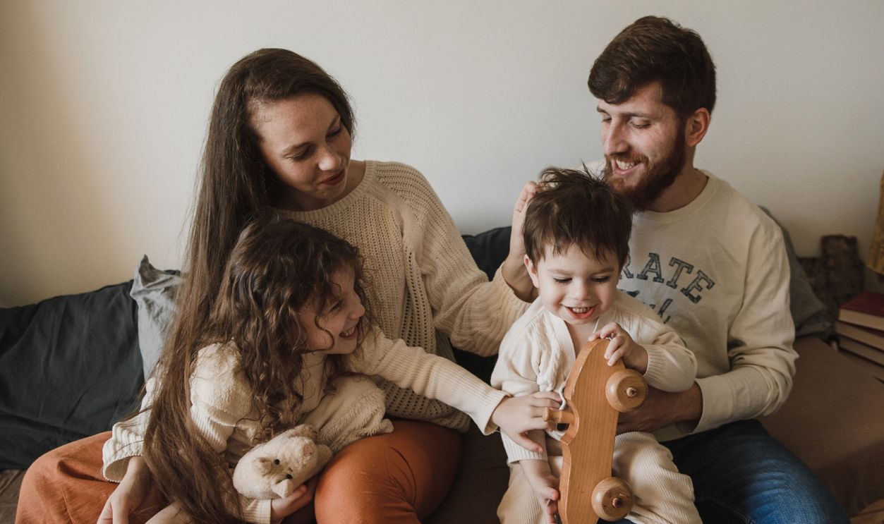A joyful family of four sitting together on a sofa