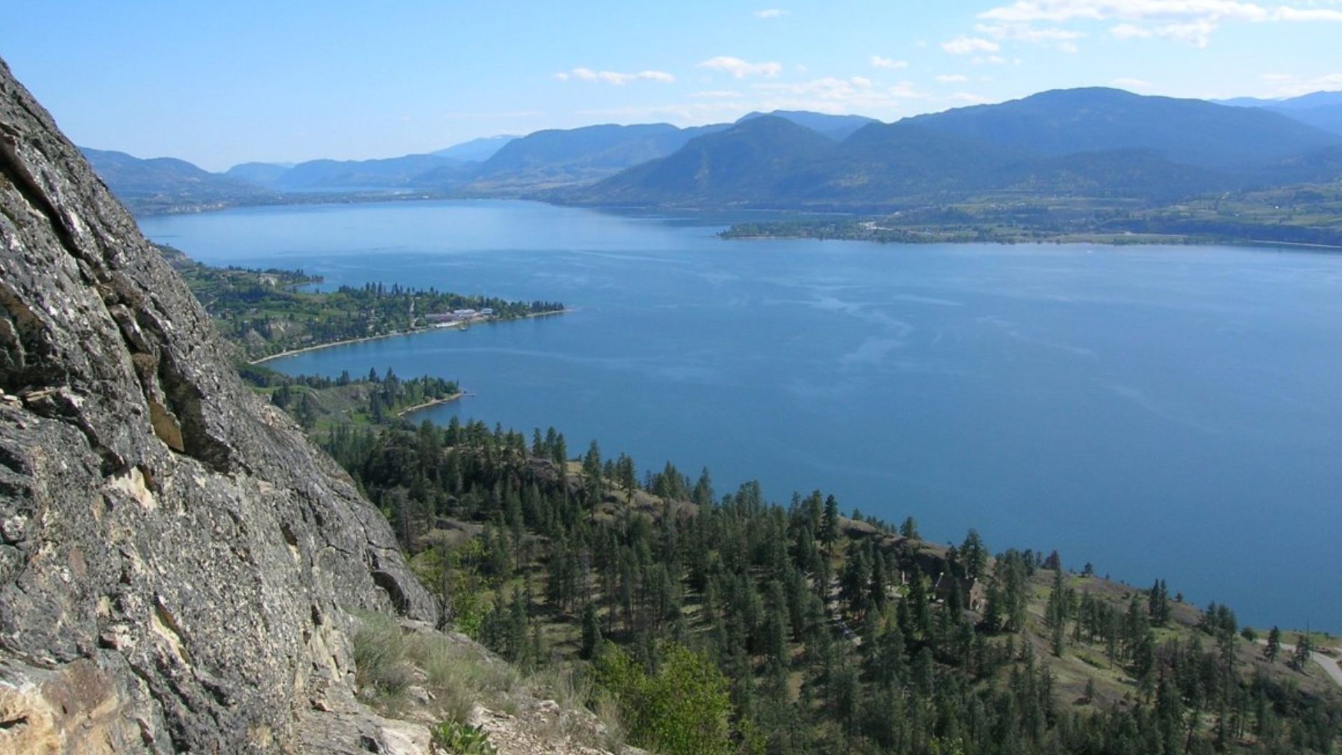 Image of the south part of Okanagan Lake, taken from the KVR trail. Summerland is on the right, Naramata the left, and Penticton is in the distance at the end of the lake. Photographed by Darren Kirby summer 2006.