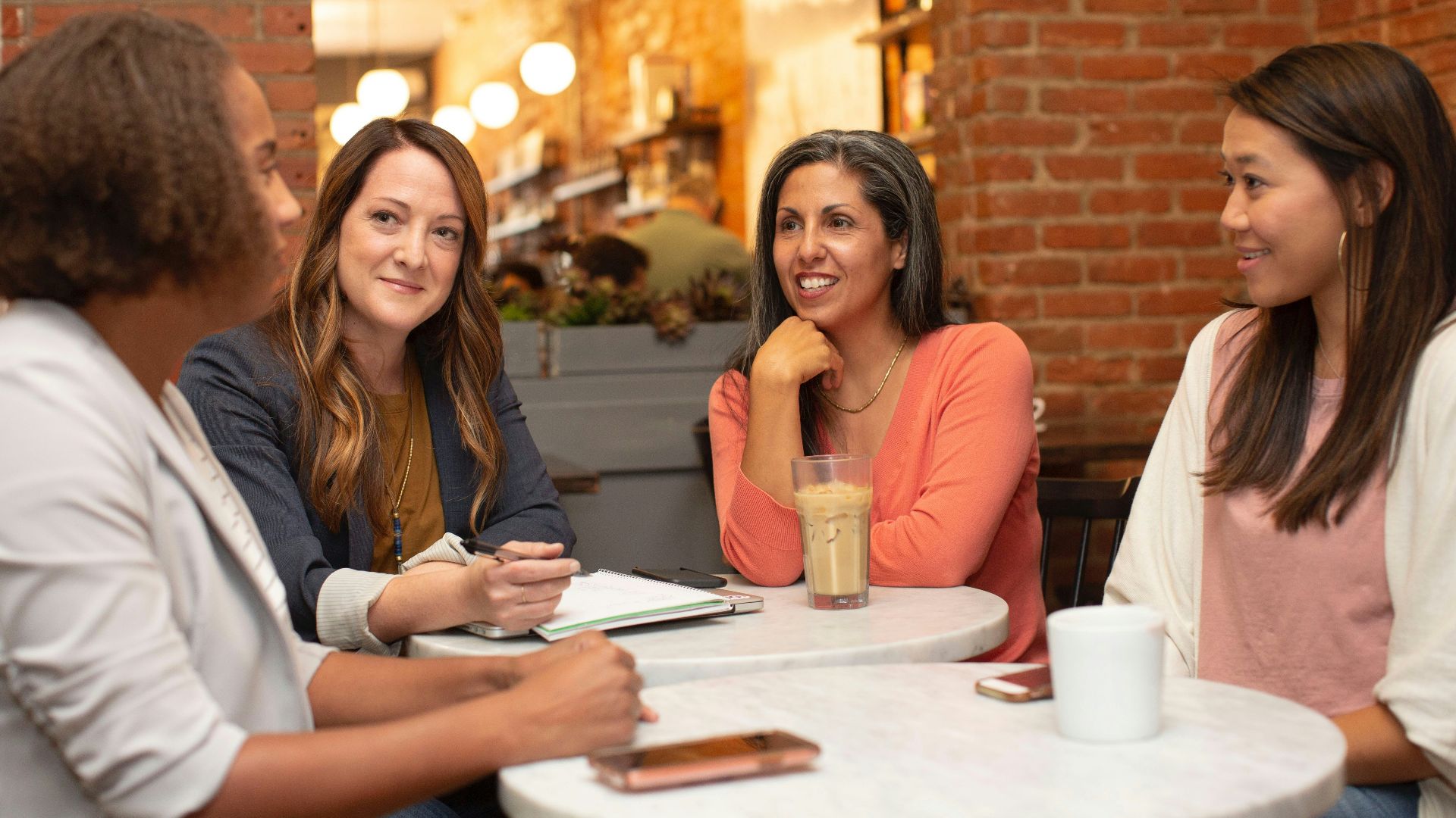 four women chatting at cafe table