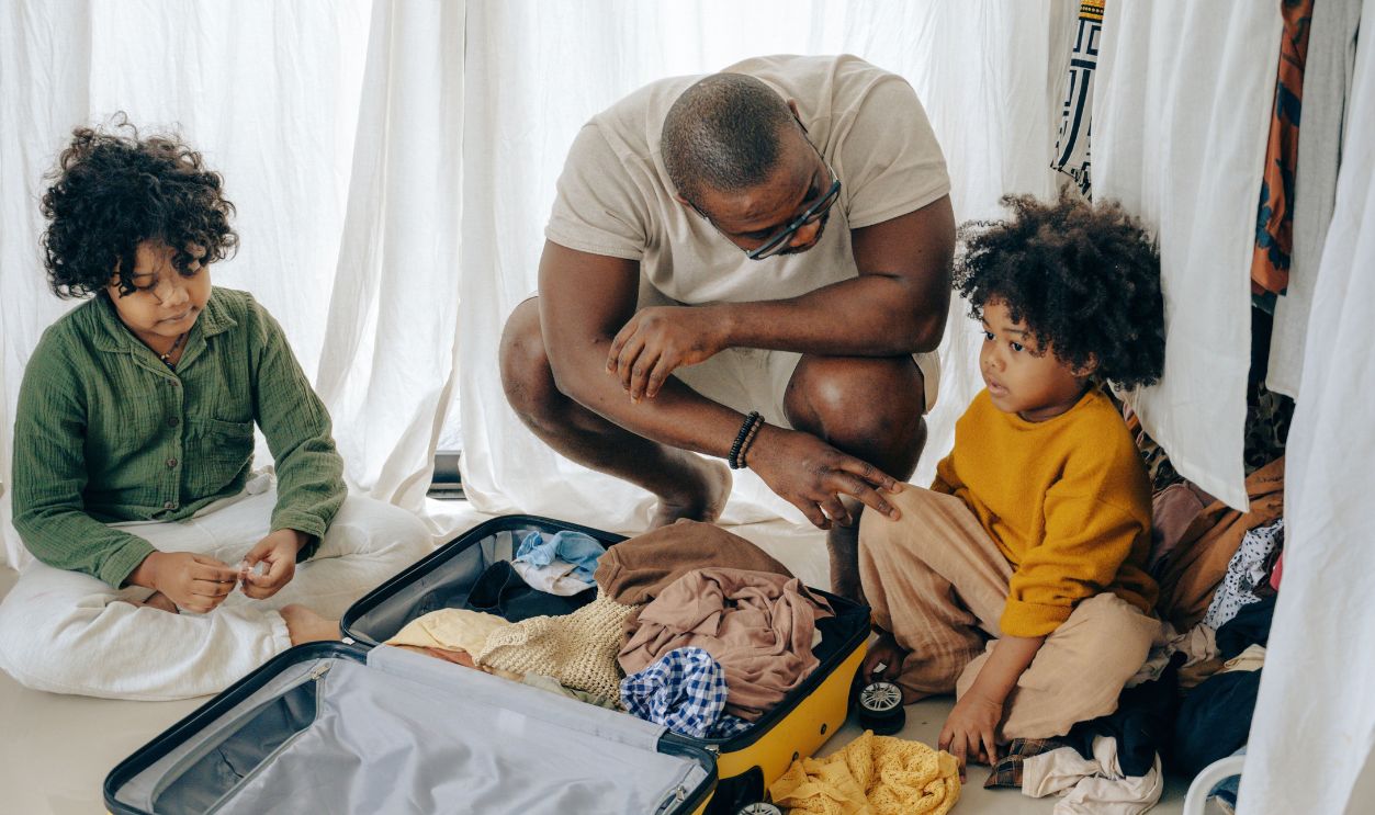 A father helps his children pack a suitcase at home